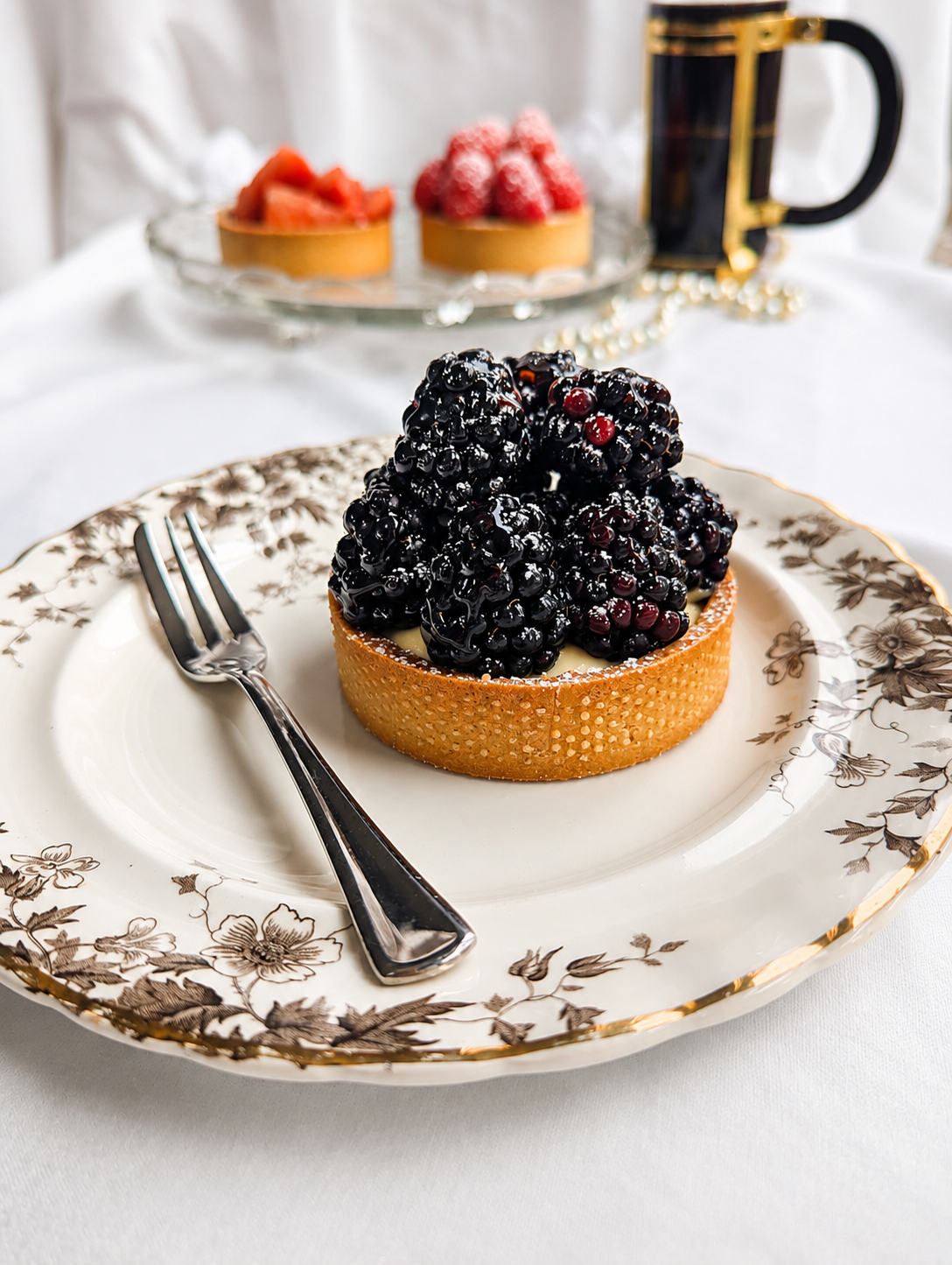 Blackberry tart on a plat with a pastry fork for our story page