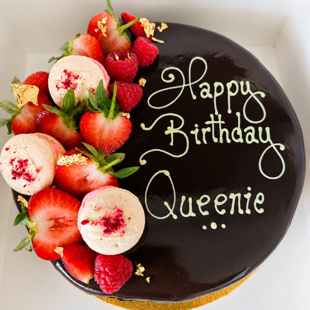 Celebration Cakes - A chocolate mousse gateau topped with fresh fruit and macarons with Happy Birthday Queenie pipped on the top