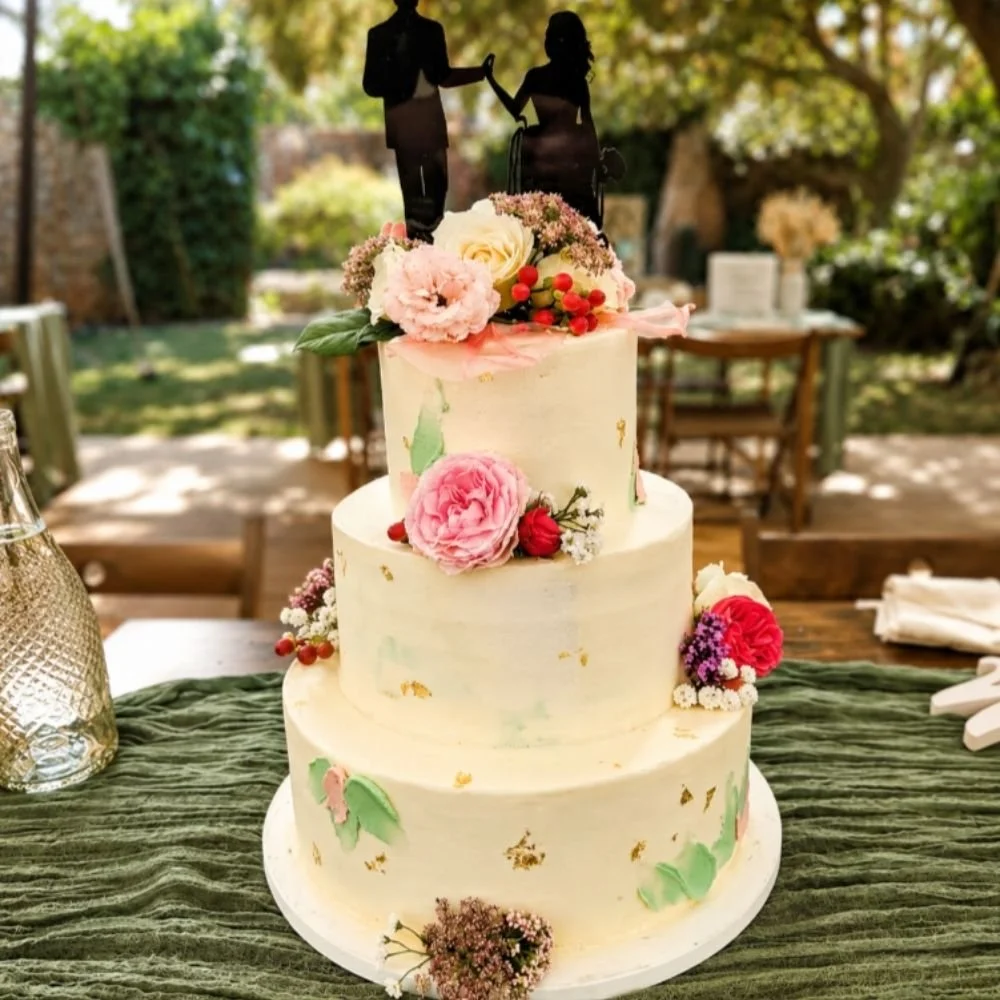 3 tiered wedding cakes with fresh flowers and a bride and groom silhouette on the top