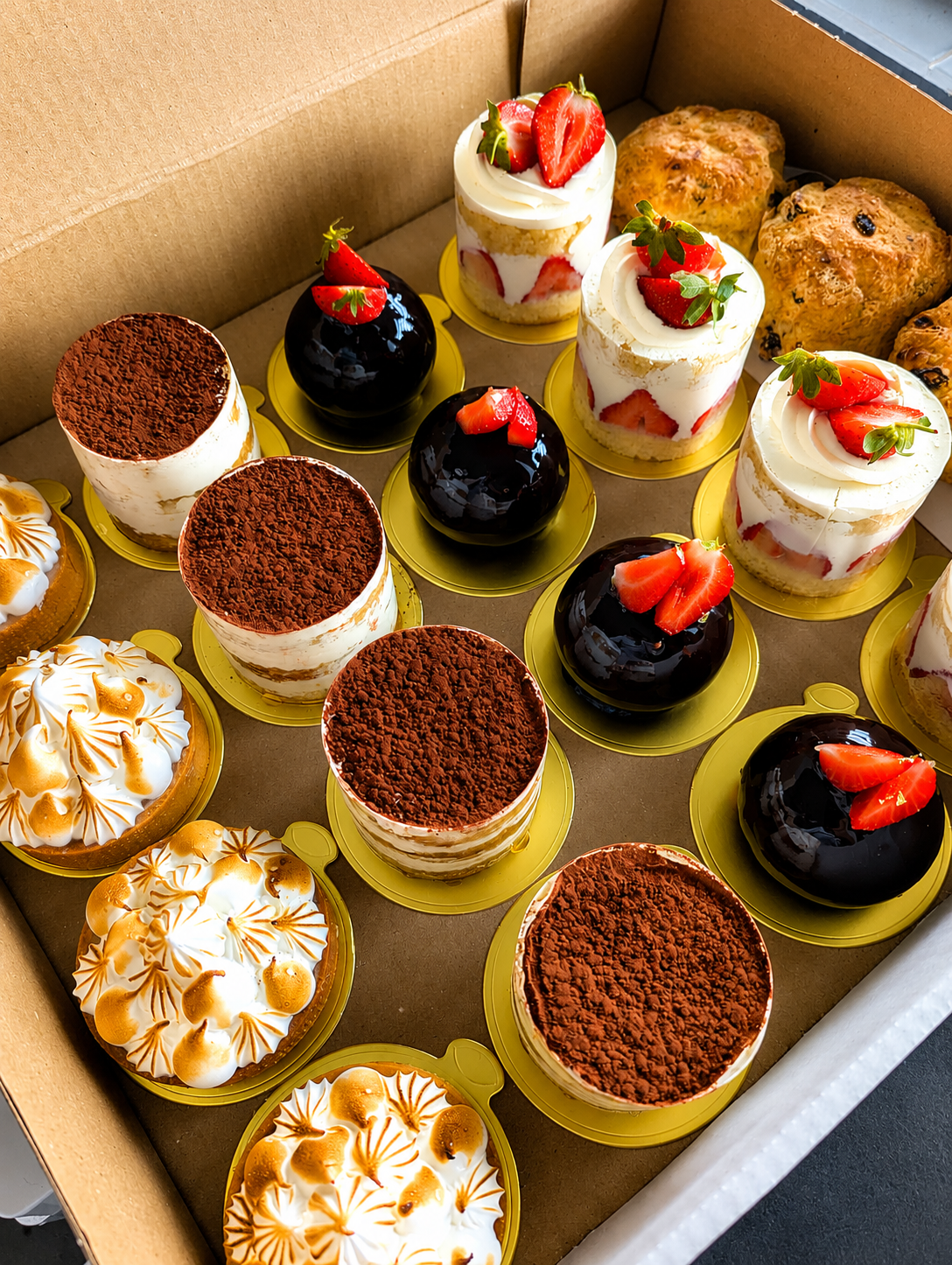 a selection of handcrafted patisseries including lemon meringue tarts and chocolate bombs