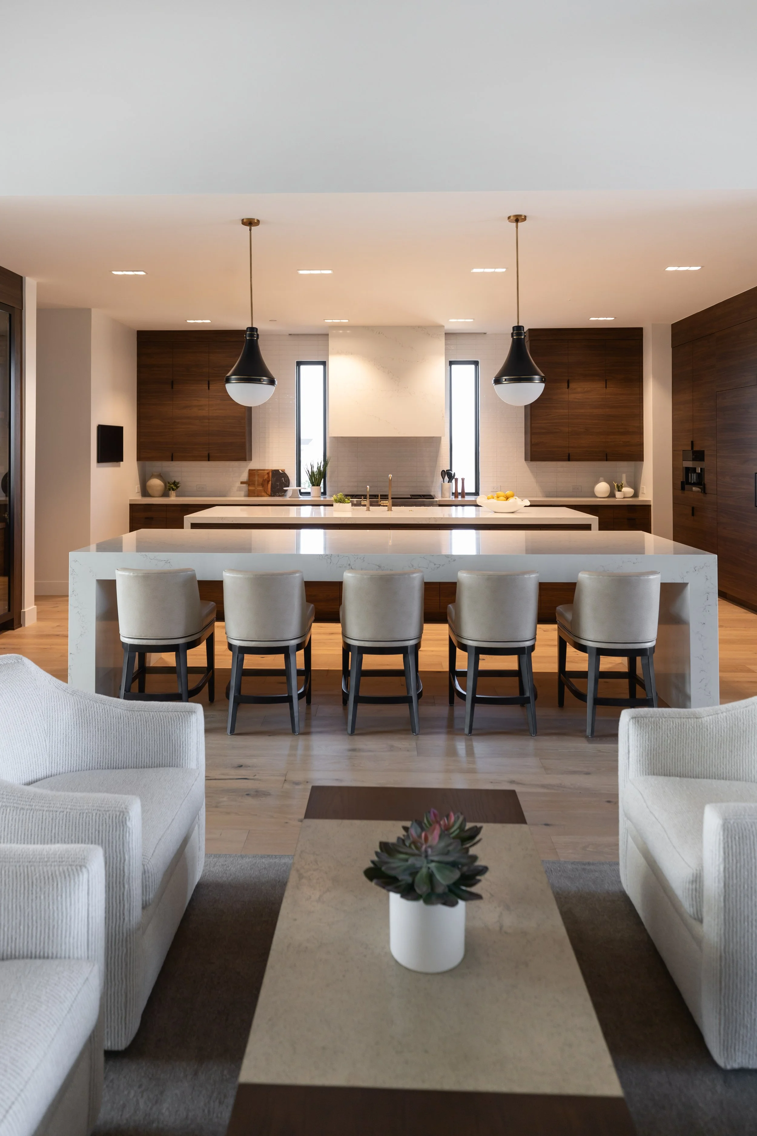 Modern Scottsdale kitchen featuring warm wood cabinetry, white waterfall island and contemporary furnishings.