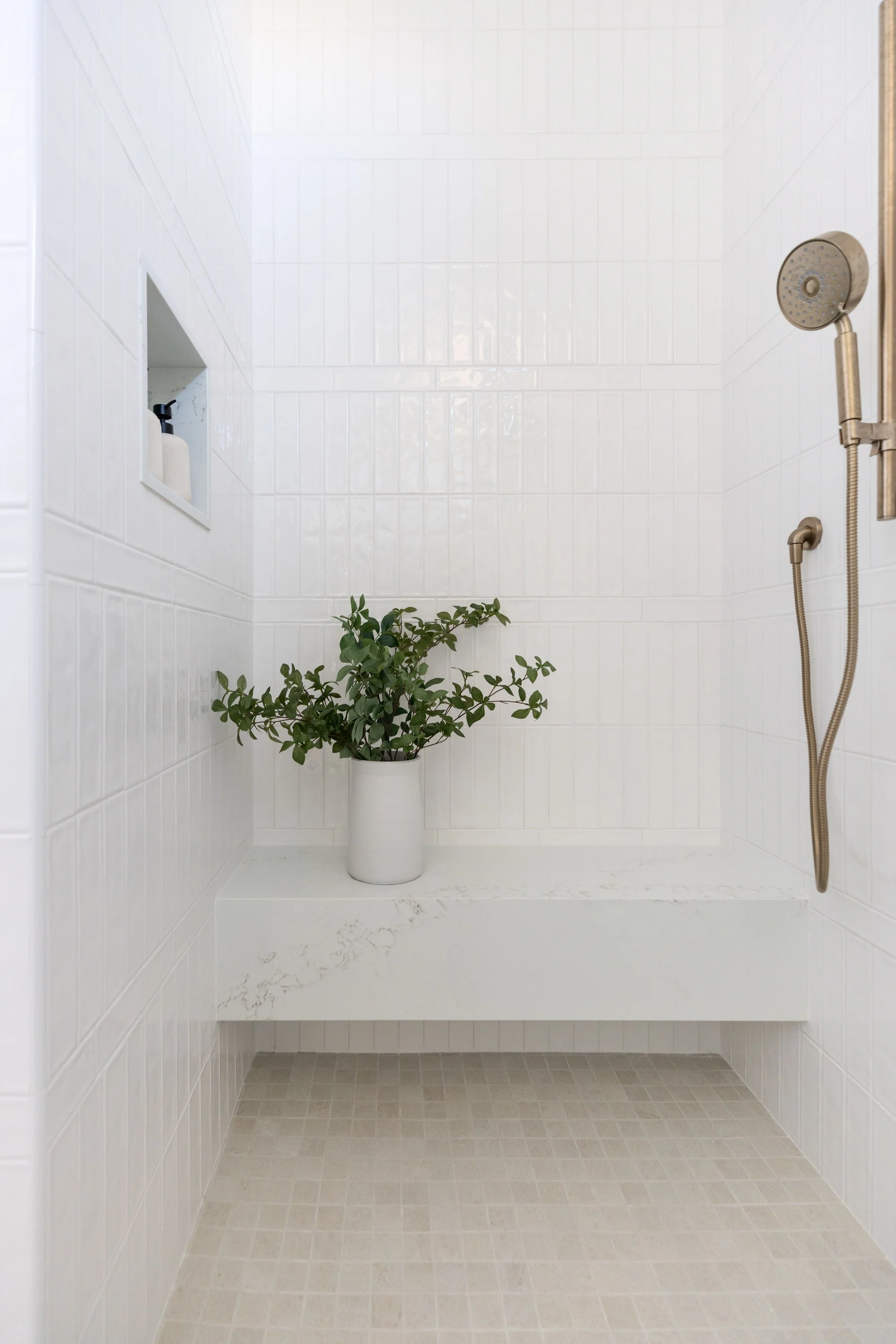 White tiled walk-in shower with custom quartz bench and built-in niche in a Scottsdale home