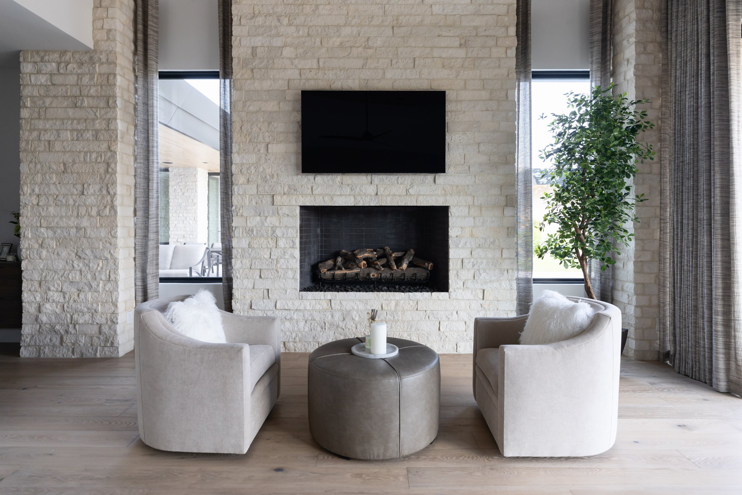 Floor-to-ceiling natural stone fireplace with black firebox and custom drapery in a Scottsdale custom home designed by Ashley Marie Interiors.