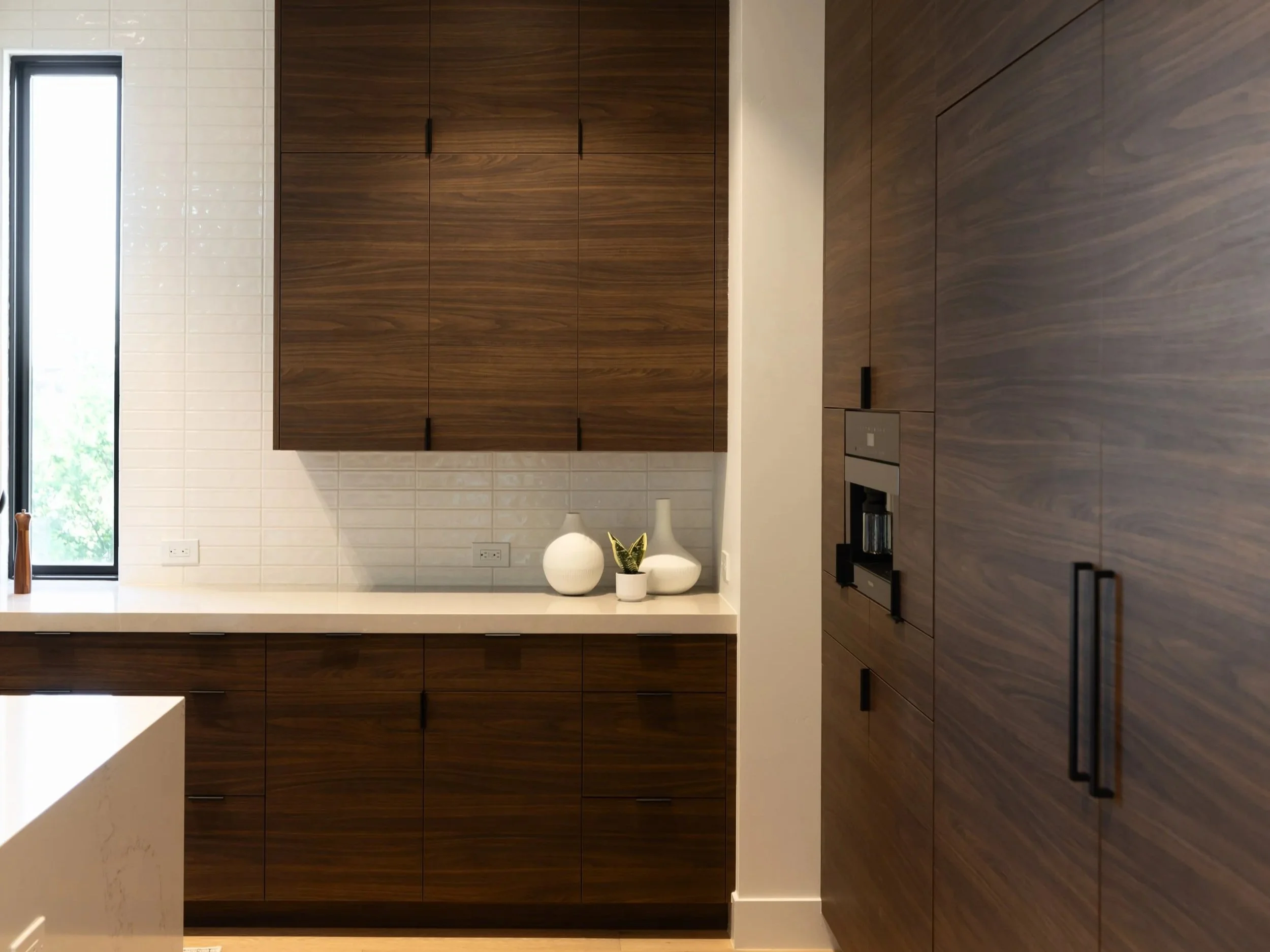 Custom walnut cabinetry with white countertops, black hardware and built-in appliances in a Scottsdale new construction home.
