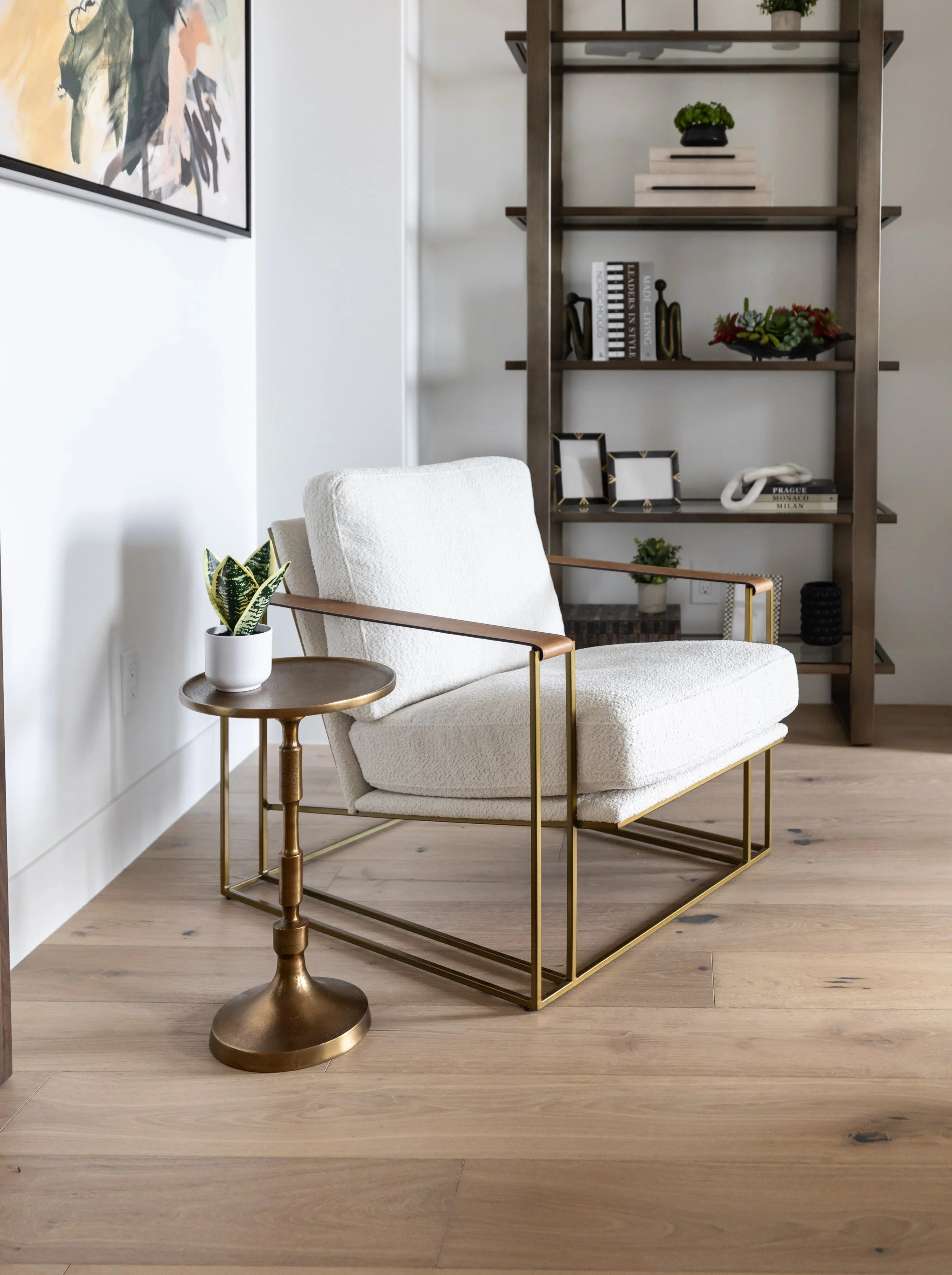 shelving.jpg White boucle accent chair with brass frame beside custom dark wood shelving in a Scottsdale interior