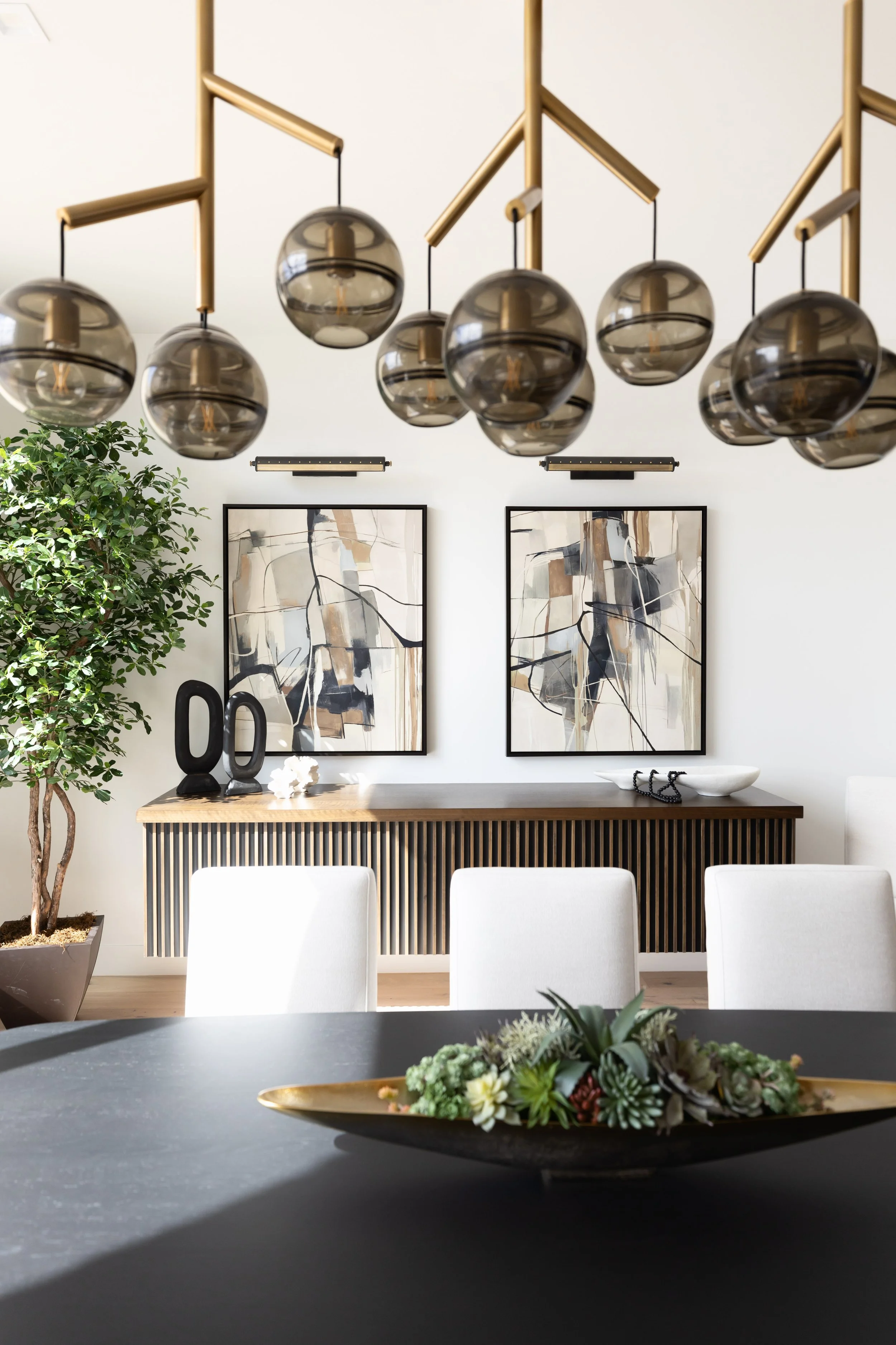 Contemporary Scottsdale dining room combining sculptural lighting, warm wood furnishings and statement artwork.