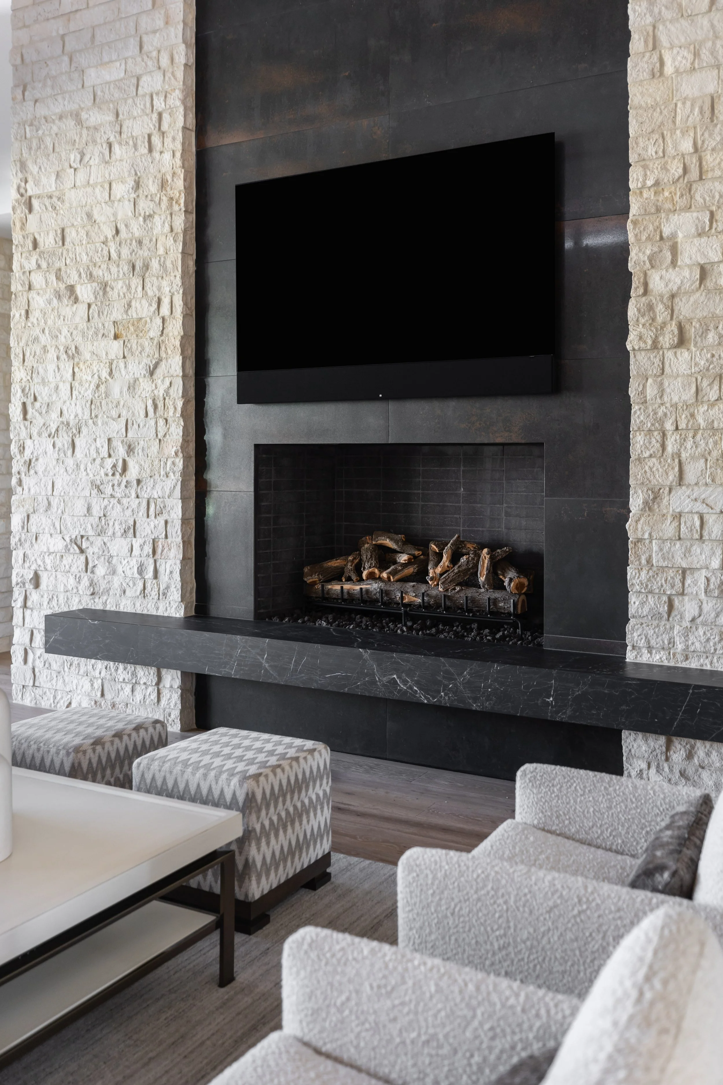 Modern Scottsdale living room with natural stone fireplace, black fireplace surround and white lounge chairs