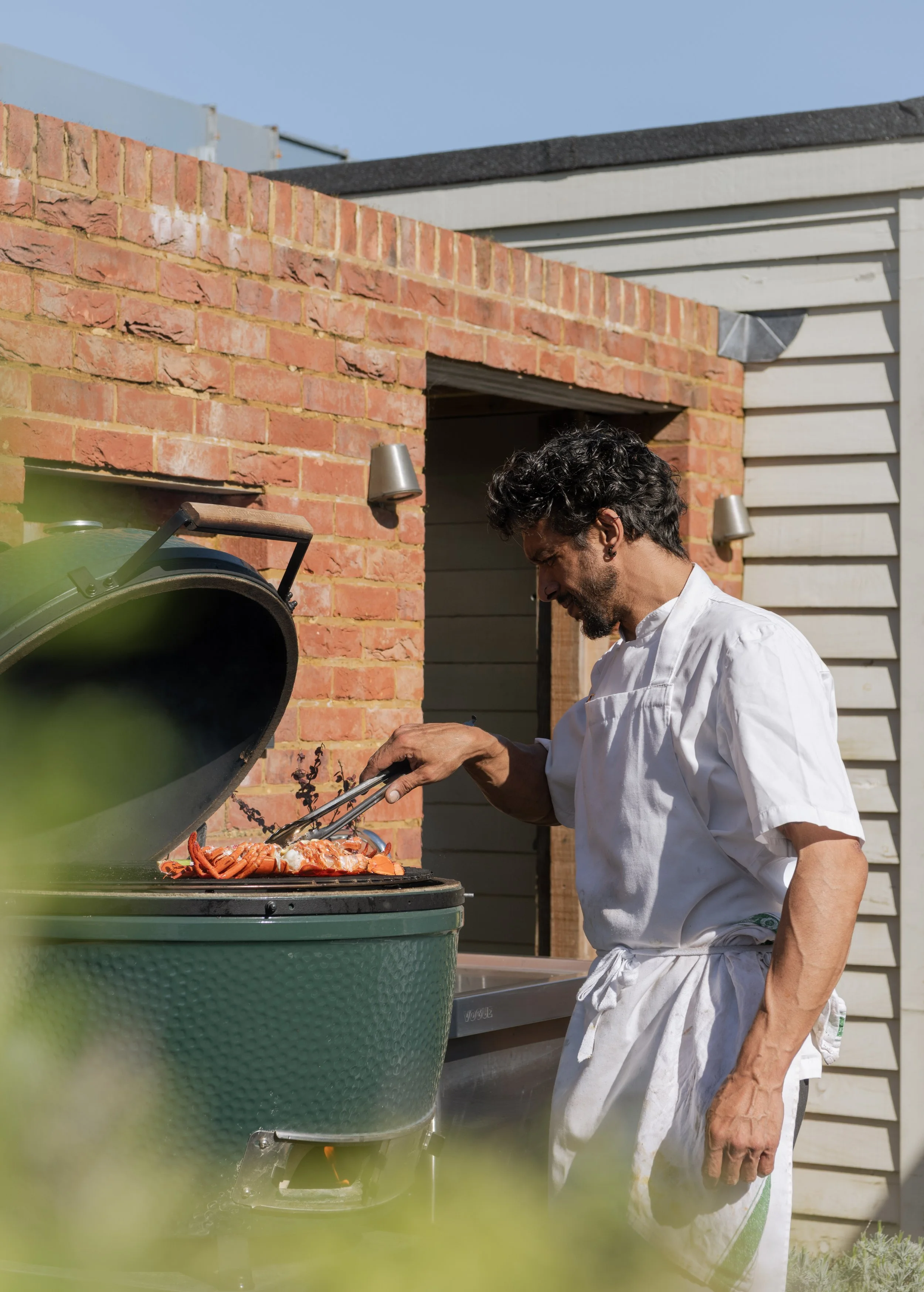 Professional chef grilling fresh lobster on a Big Green Egg for the Easter Monday barbecue at The Woodcote.