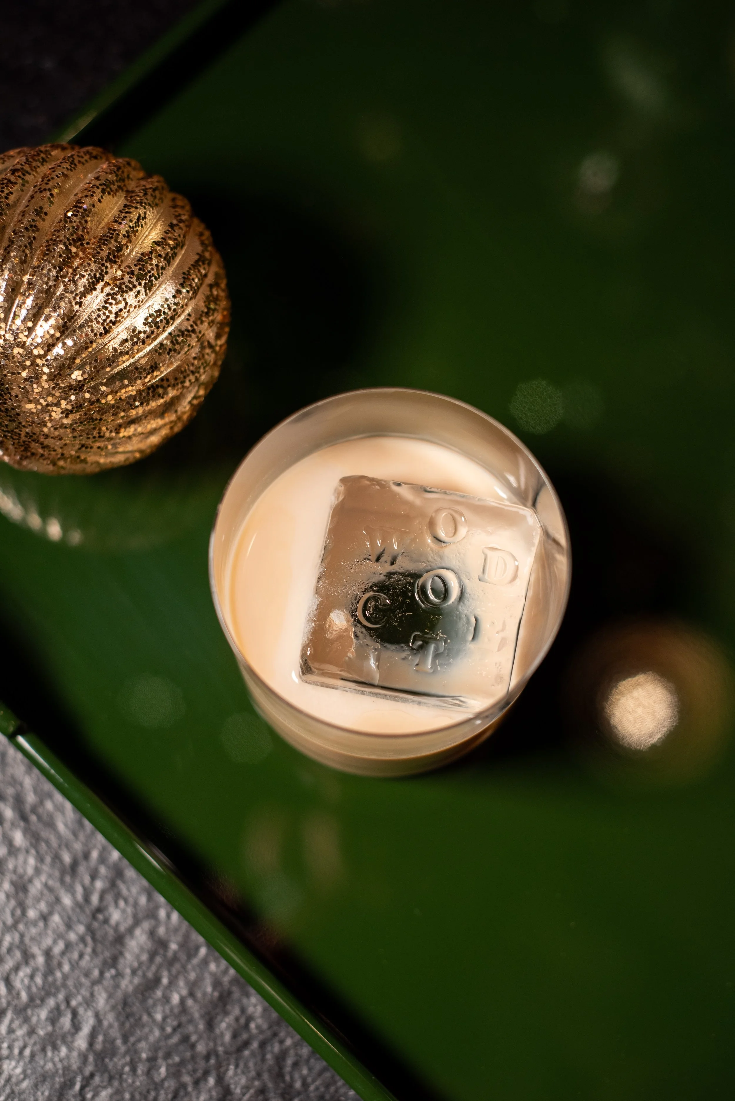 Festive cocktail with a Woodcote-branded ice cube beside a Christmas bauble in Graffham, West Sussex.