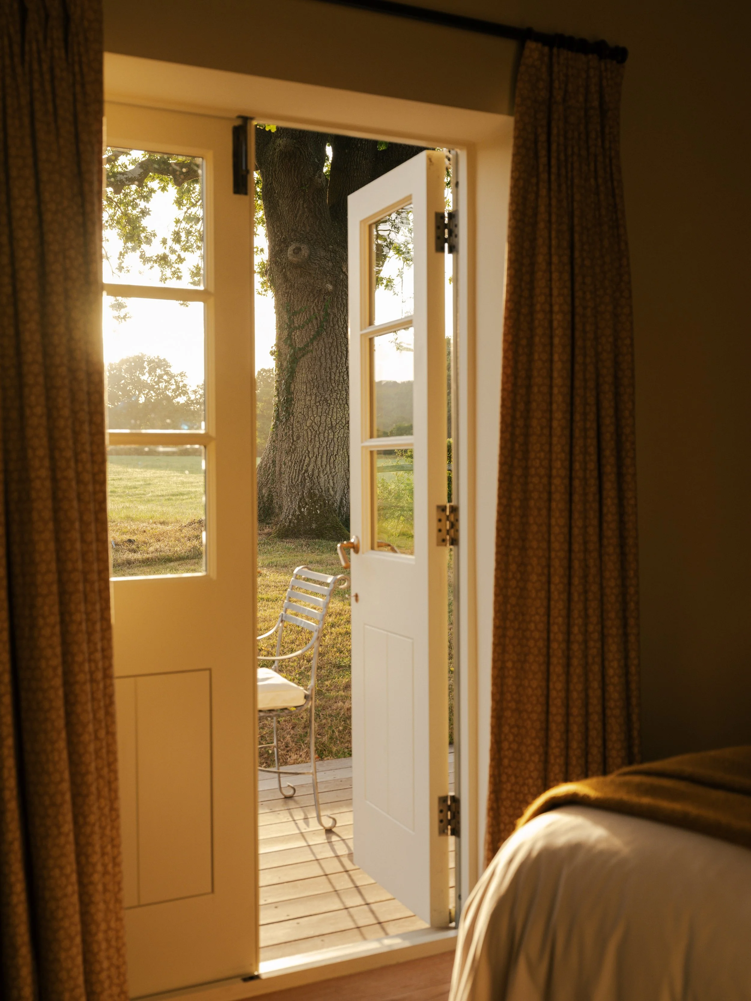 The Woodcote guest room with open doors overlooking the South Downs countryside.