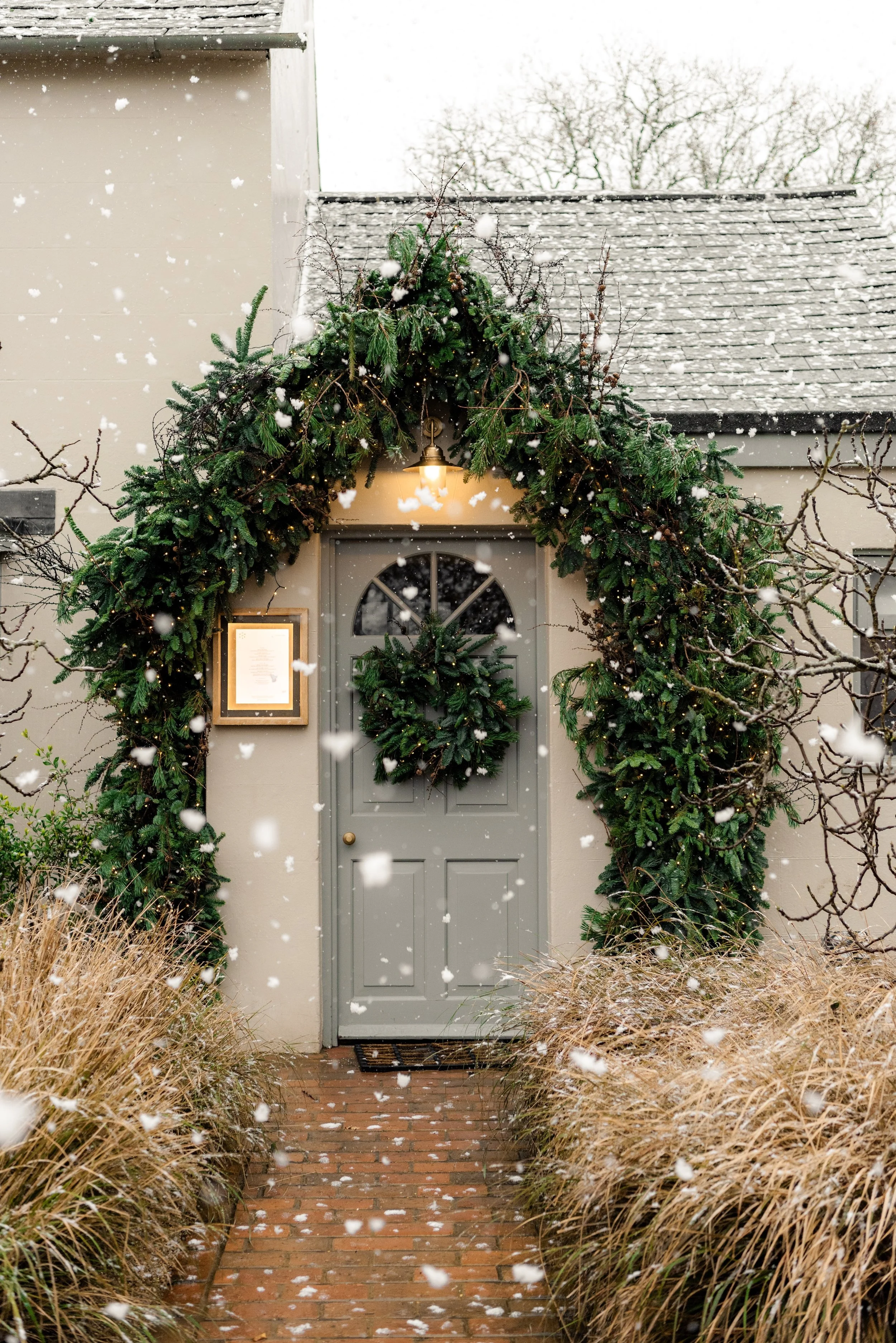 Snow falling around the Christmas-decorated entrance to The Woodcote in Graffham, West Sussex.