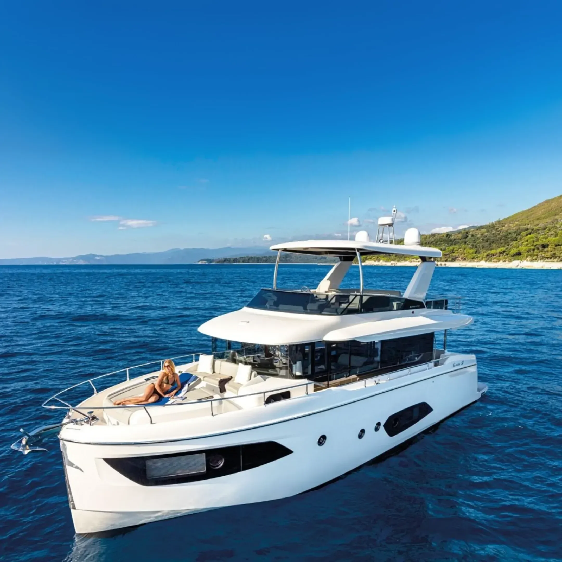 kokomo charters - 52' Rally Point - A white luxury yacht sailing on calm blue ocean waters near a green coastline under a clear blue sky.