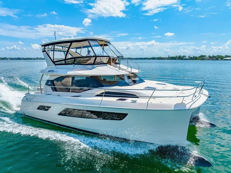 kokomo charters - 50' Memory Maker - A white motor yacht cruising on a calm body of water under a partly cloudy sky.