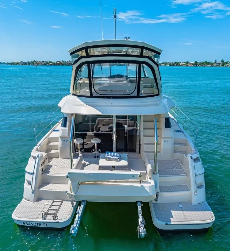 kokomo charters - 50' Memory Maker - A luxury white yacht docked in turquoise water off the coast of Sarasota, Florida, with a view of nearby shoreline and buildings in the background.