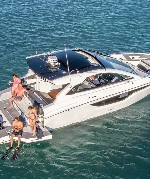 kokomo charters - 43' Giddy Up - A white luxury motor yacht floating on the water with five people on board, some sitting and some standing; two people are using snorkel fins in the water beside the boat.