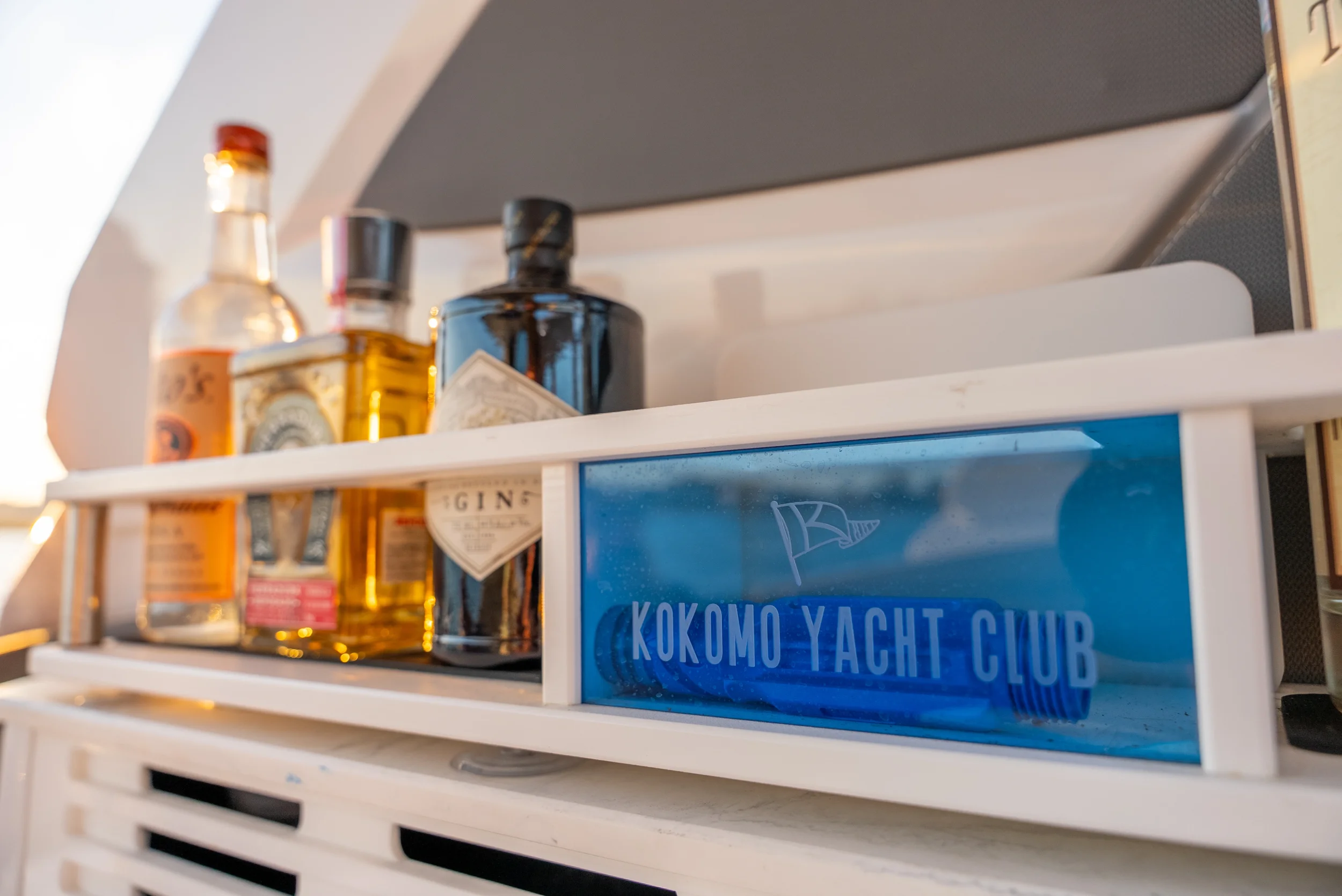 Kokomo charters - St. Pete sunset cruise -  Yacht bar with bottles of liquor and a blue sign that reads 'KOKOMO YACHT CLUB'.