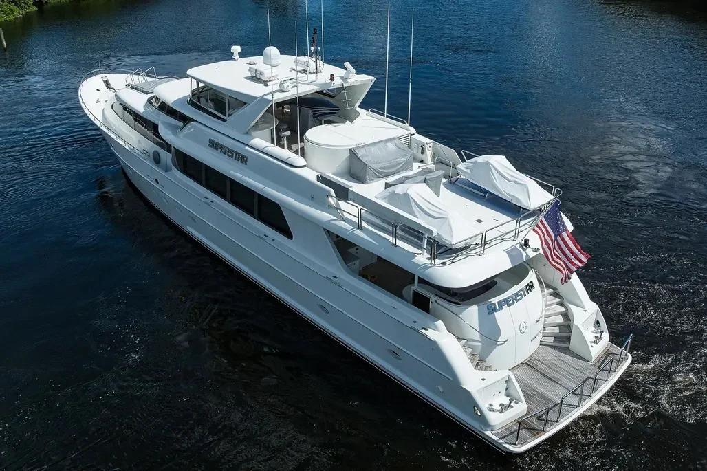 Kokomo charters - Sarasota sunset cruise - A large white luxury yacht cruising on water with an American flag at the stern and interior covered with protective tarps.