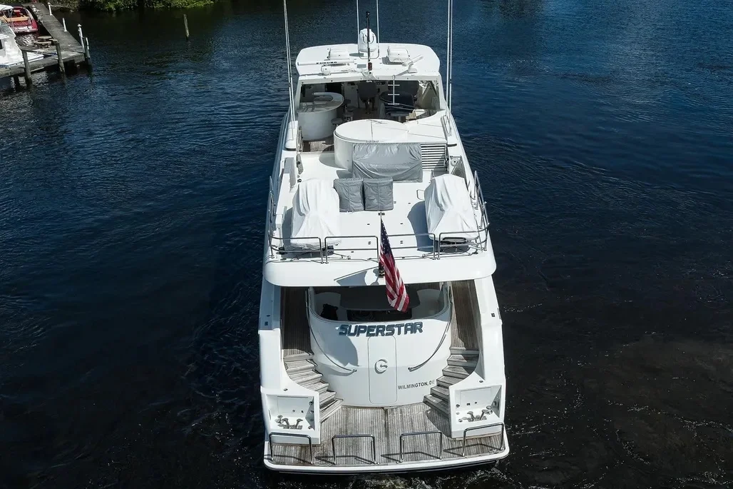 Kokomo charters - Sarasota sunset cruise - Top-down view of a white yacht named 'SUPERSTAR' docked in a marina, with a flag on the stern, water surrounding it, and a small dock in the top left corner.