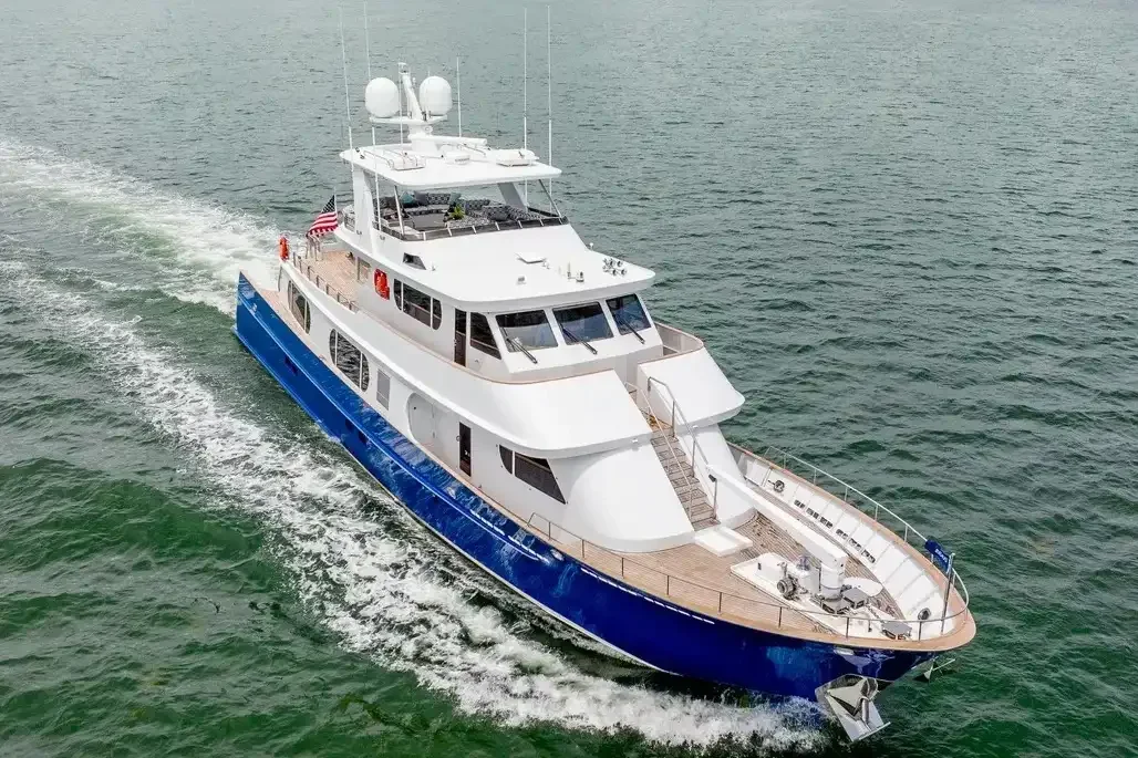 Kokomo charters - luxury yacht charter - A white and blue luxury yacht sailing on the ocean, with American flags on board.