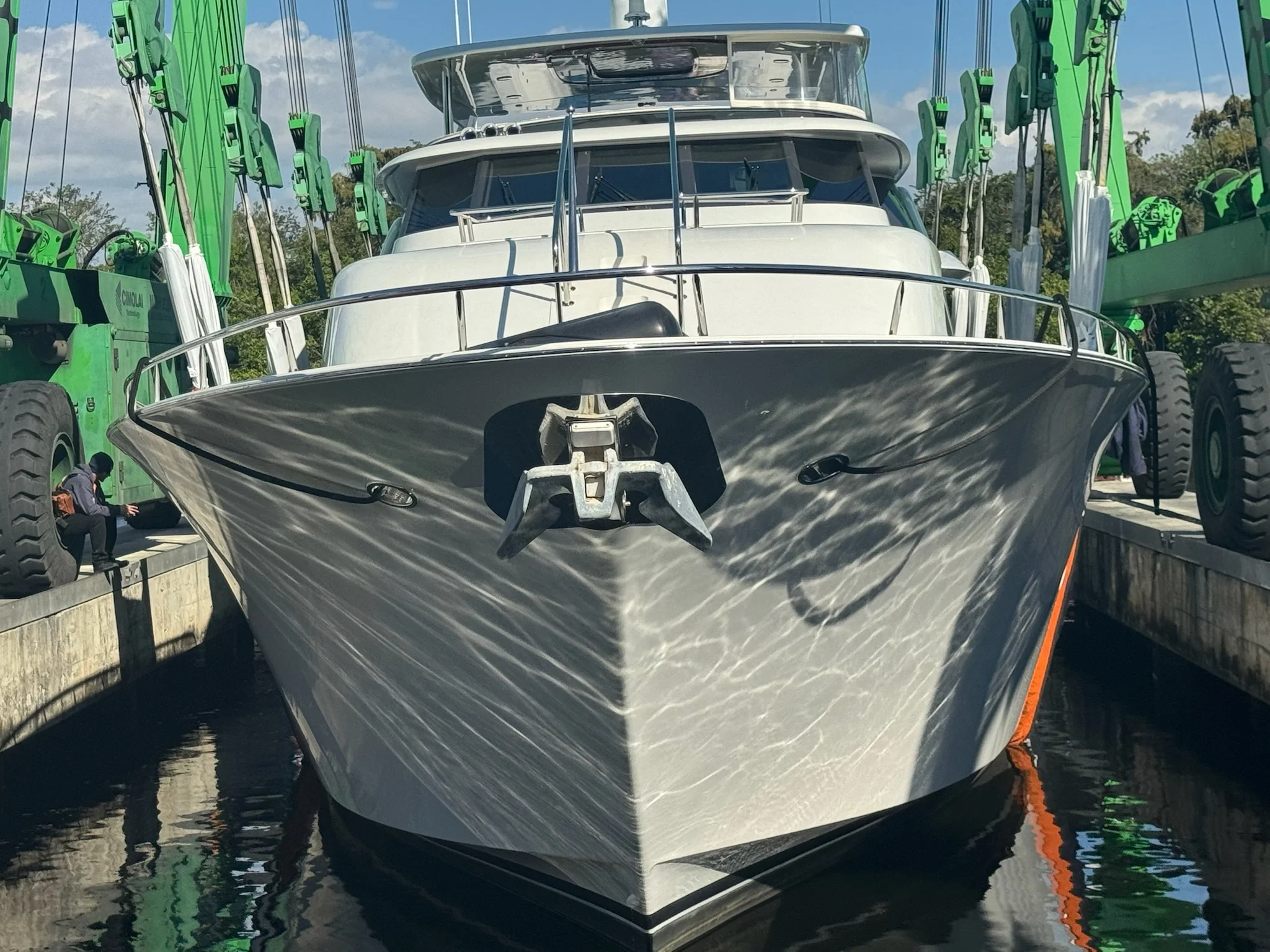 Kokomo charters - Sunset cruises on the Gulf - Front view of a large white yacht docked in a marina, with green construction cranes on either side.