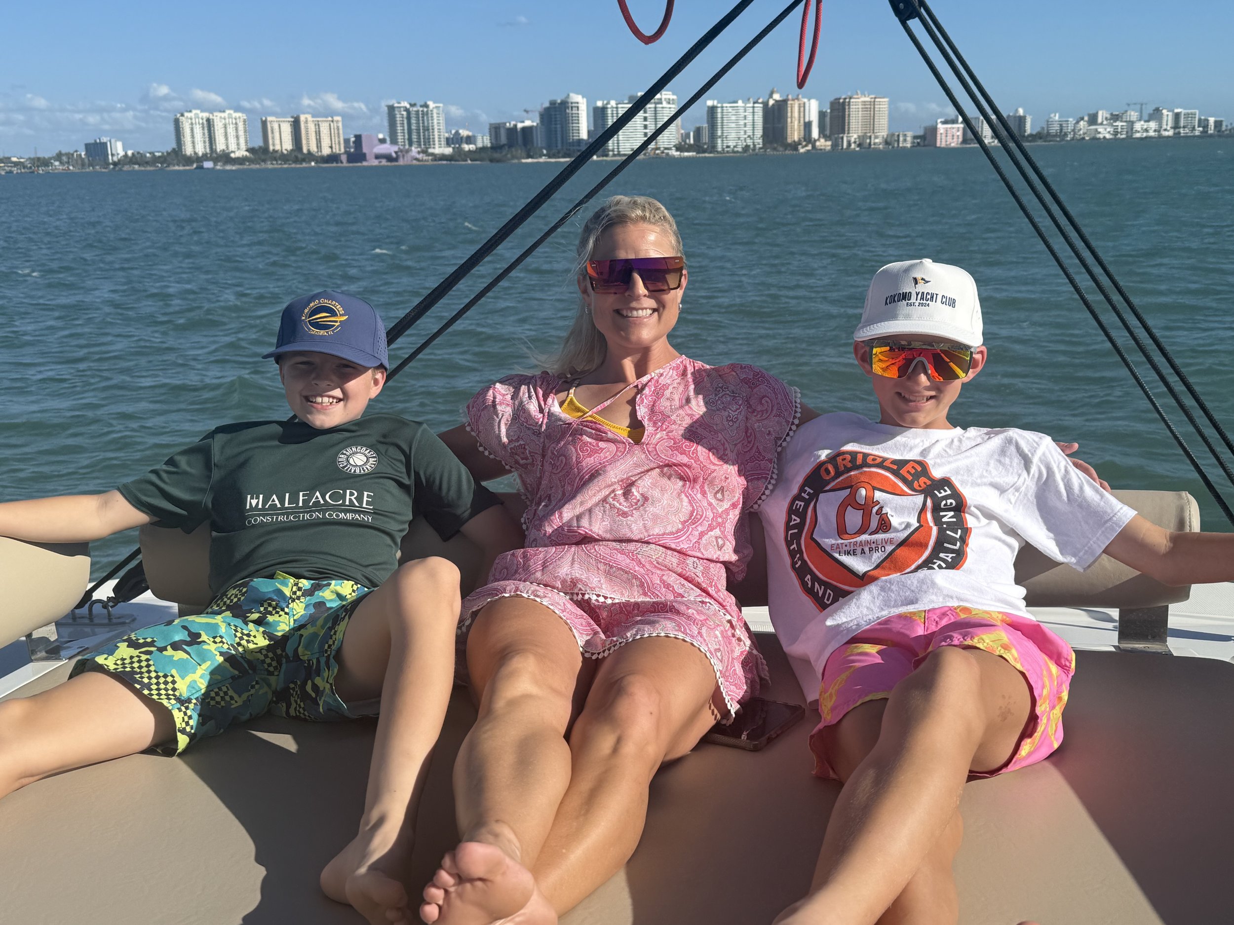 Three people relaxing on a boat with city skyline in the background.