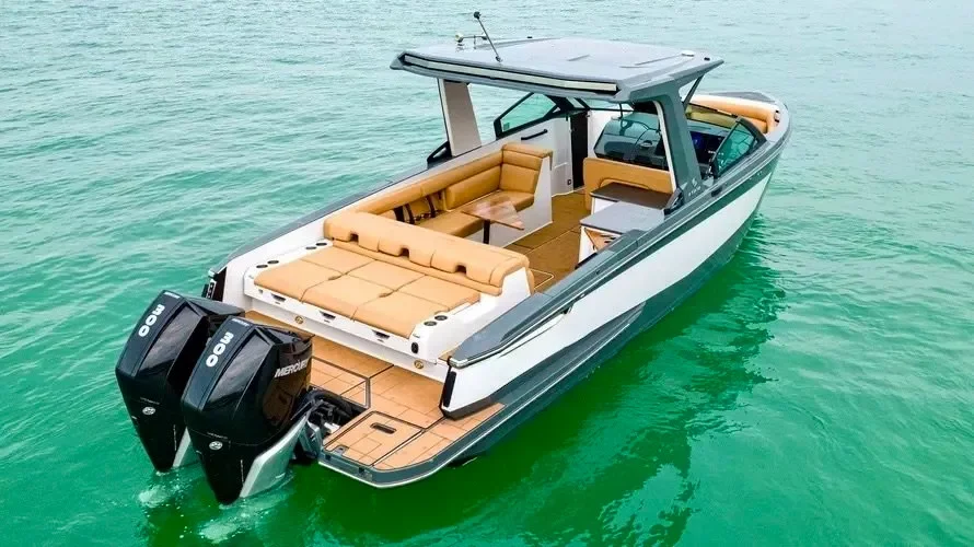 kokomo charters - 35' Ocean Rode - A modern motorboat with twin outboard engines floating on clear green water, featuring a spacious deck with tan cushioned seating and a helm area under a canopy.