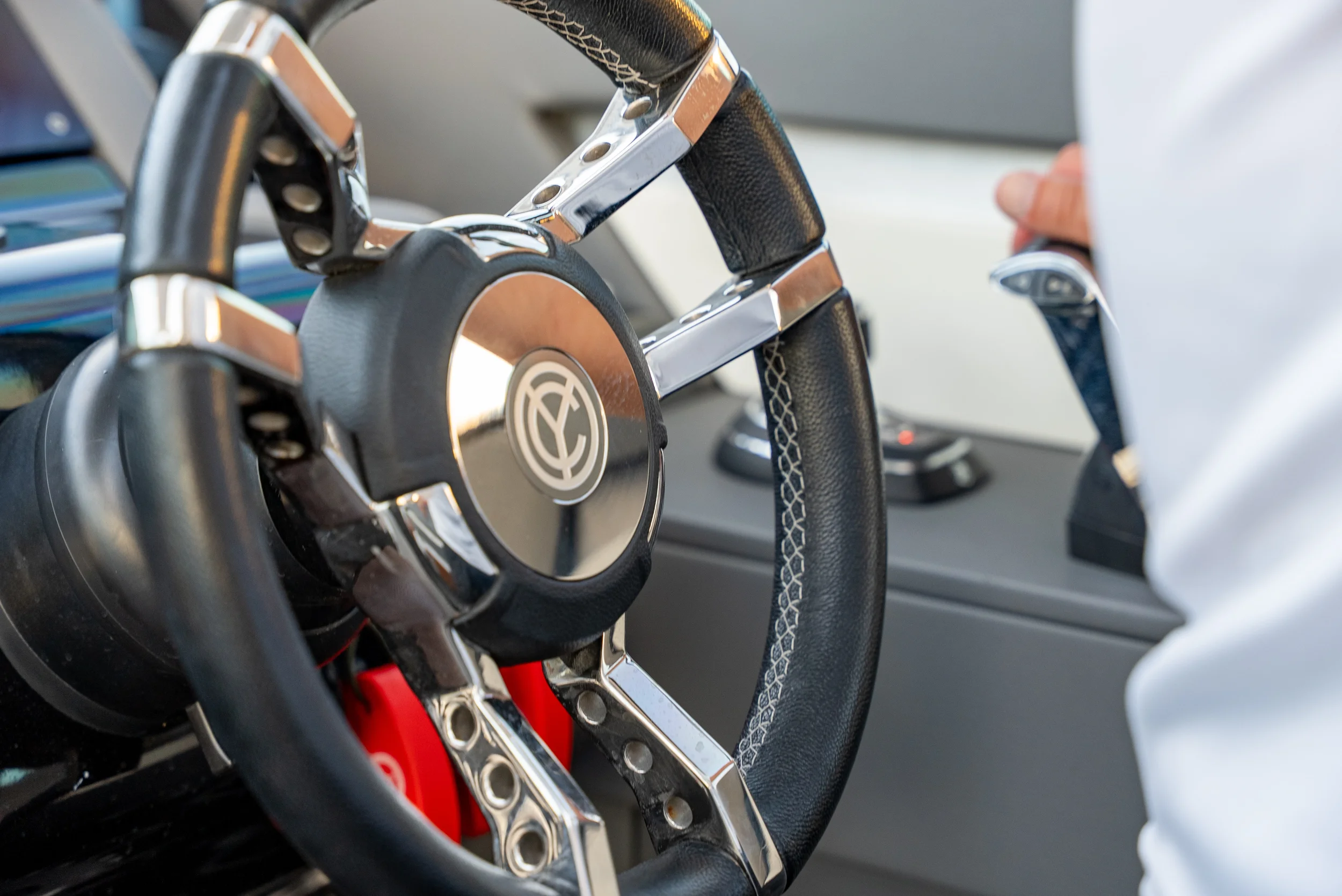 Kokomo charters - Sarasota private yacht charter - Close-up of a car steering wheel with a person holding a remote control nearby.