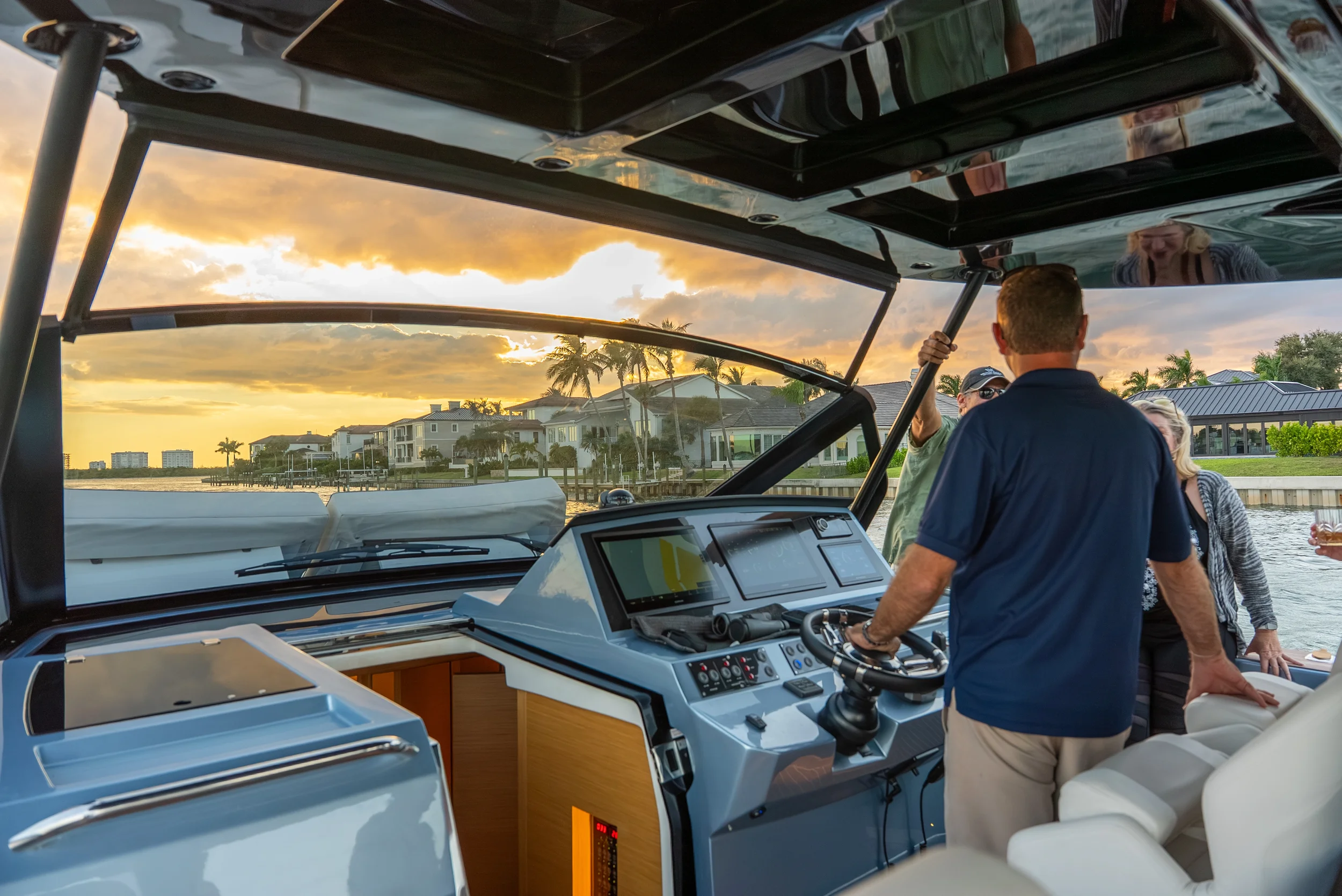 Kokomo charters - yacht float plan Sarasota - Group of people on a yacht during sunset, with waterfront houses and palm trees in the background.