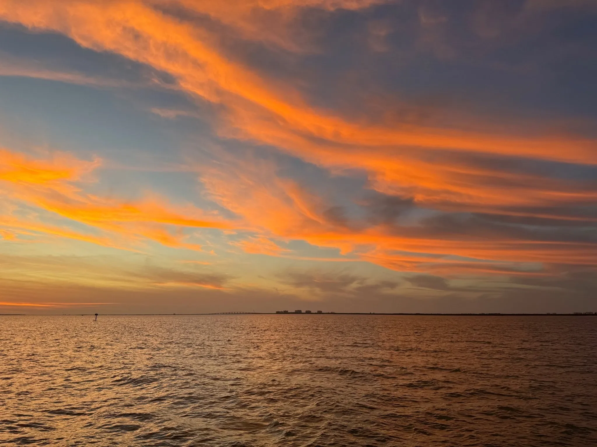 kokomo charters - rates - A group of people enjoying drinks on the deck of a yacht during a sunset cruise.