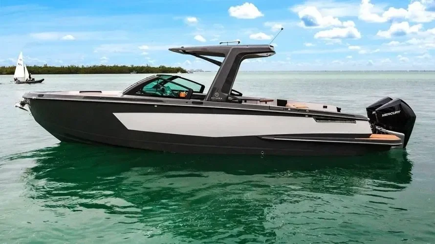 kokomo charters - 35' Ocean Rode - A sleek black and white motor yacht with an enclosed cabin, cruising on calm water under a partly cloudy sky, with a sailboat in the background.