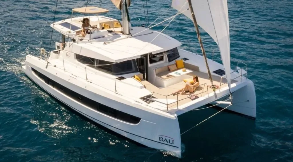 A luxury white yacht named Bali sailing on the ocean with two women relaxing on the deck.