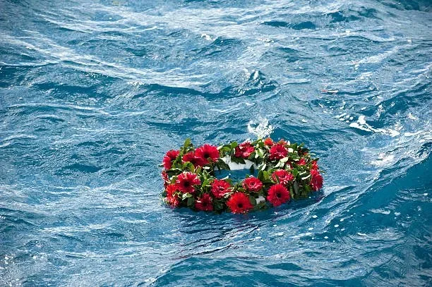 A floral wreath with pink and red flowers floating on the surface of the water.