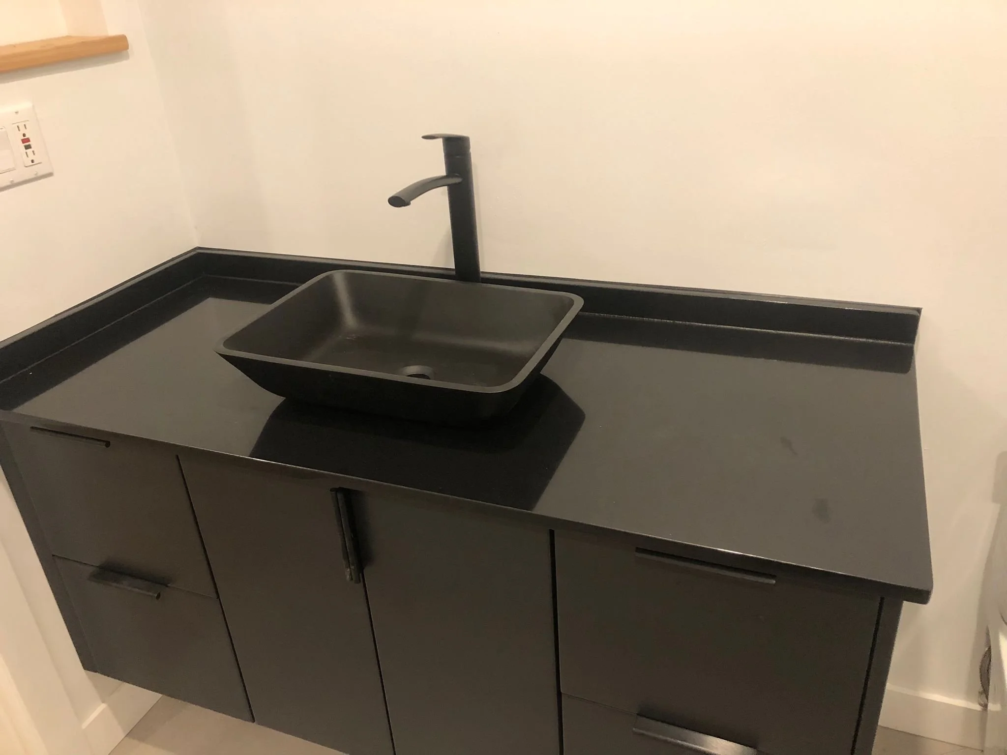 Modern black bathroom vanity with rectangular sink and faucet