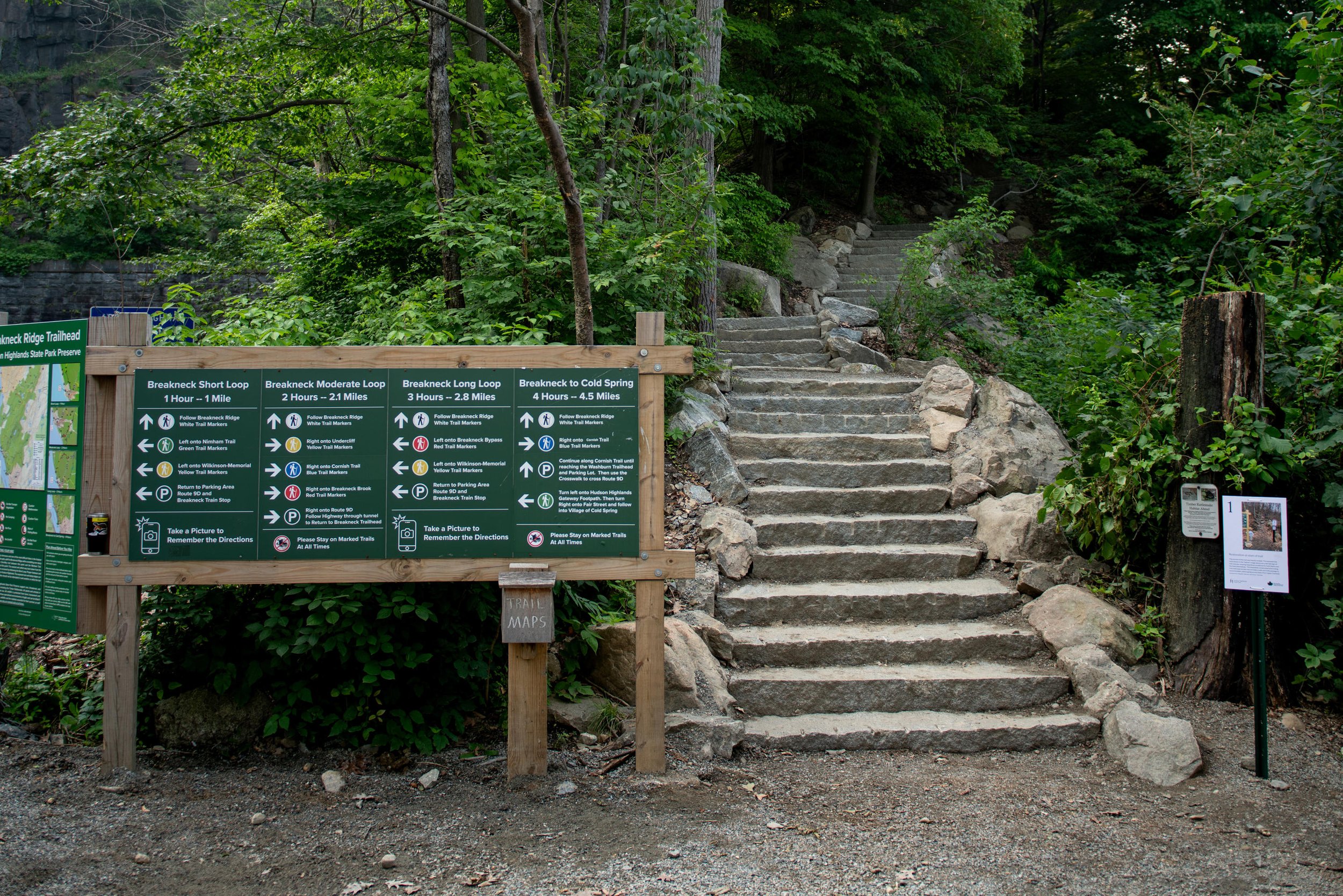 Breakneck Ridge Trailhead sign and stone steps in a wooded area.