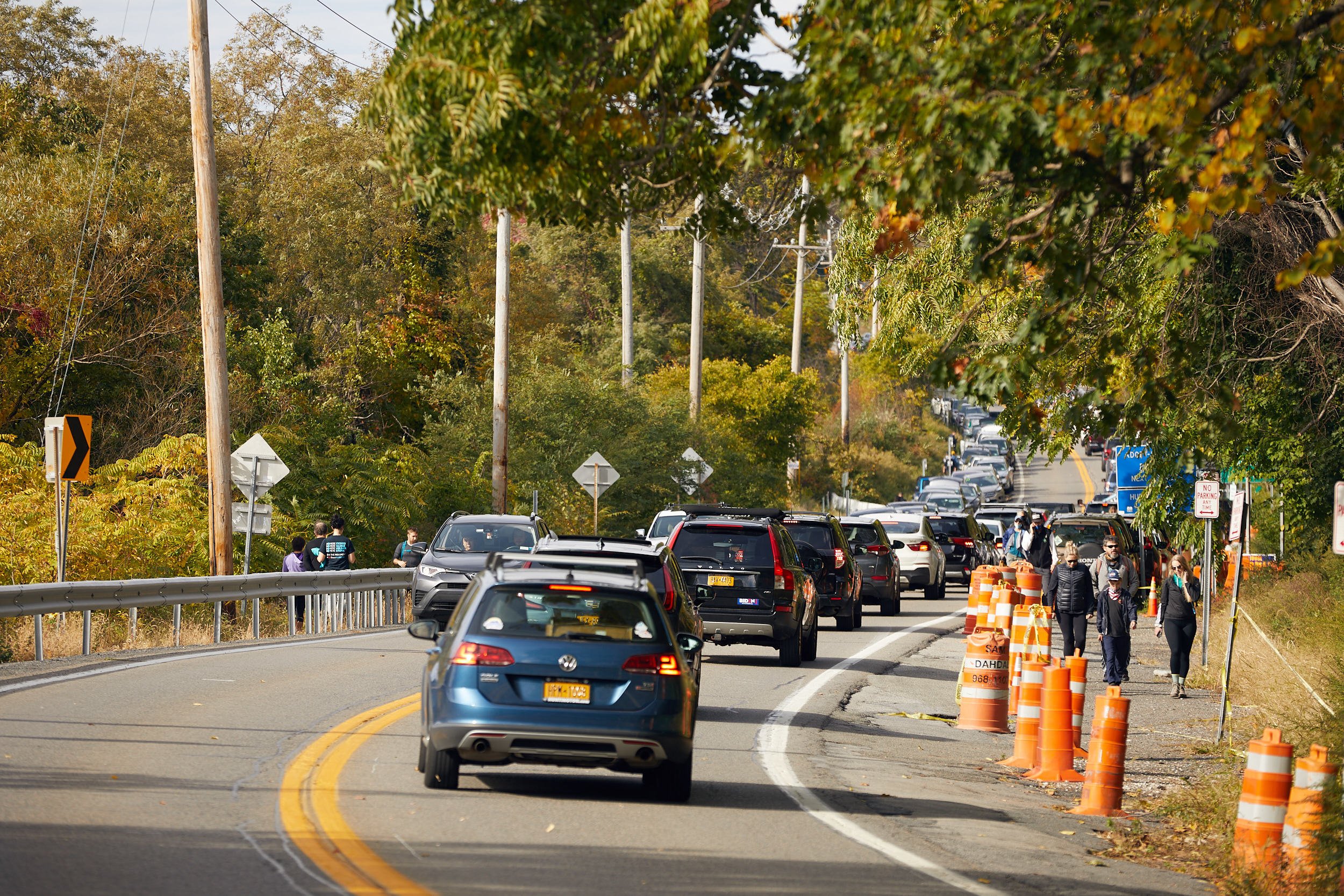 Traffic jam on Route 9D with orange construction cones, cars lined up, people walking on the side going to and from Breakneck Ridge, and trees in the background.