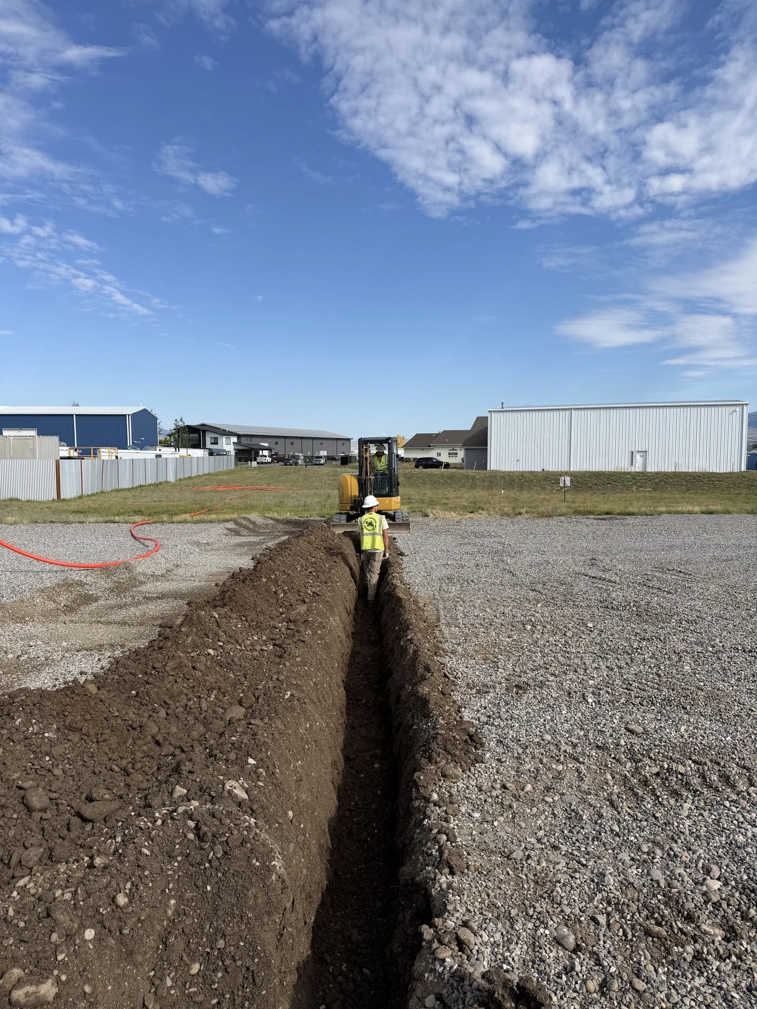 Trench for new fiber conduit across a gravel lot on a biomedical campus