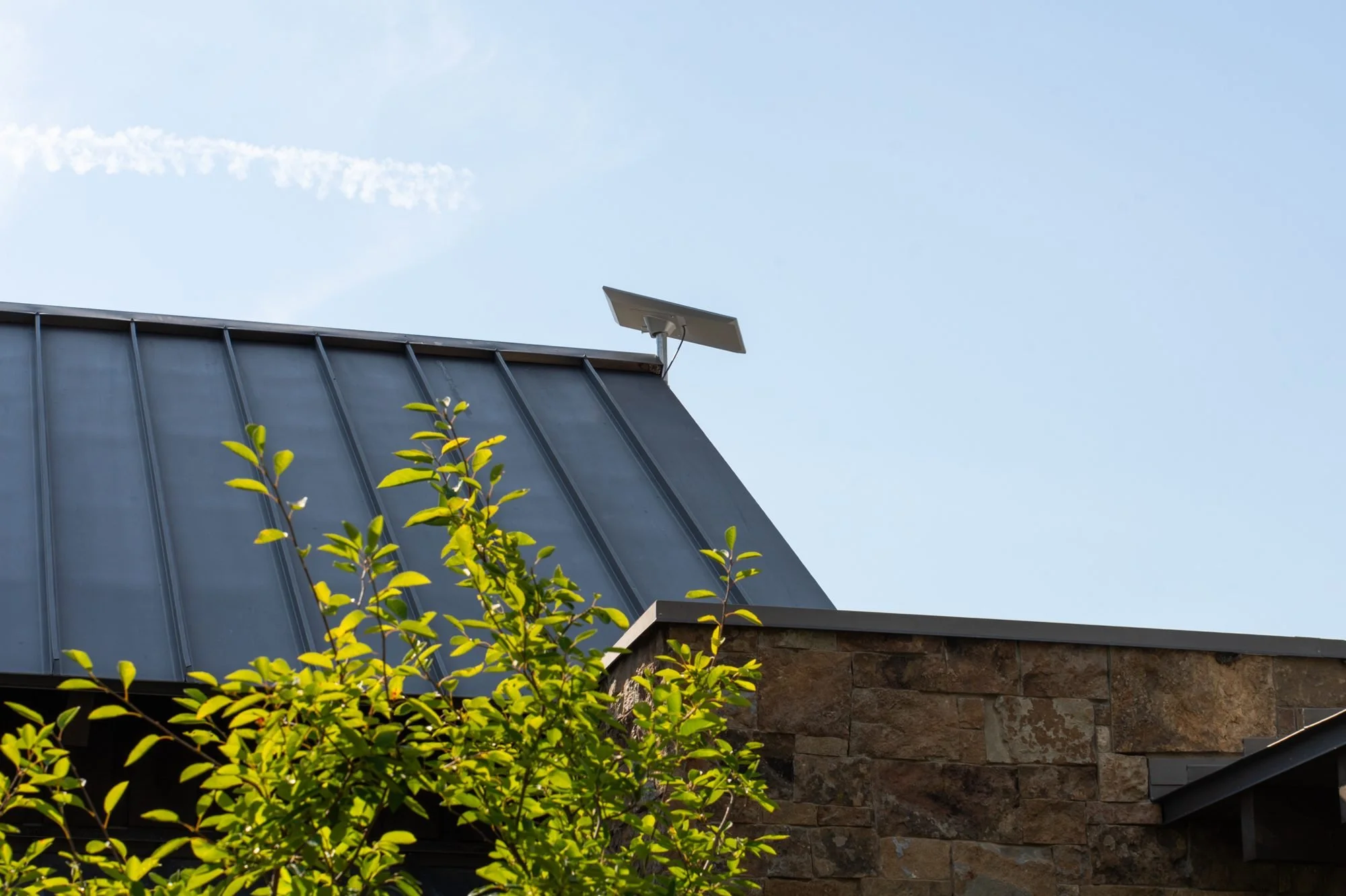 Starlink dish mounted on the metal roof of a timber and stone mountain home, installed by Big Sky Wired
