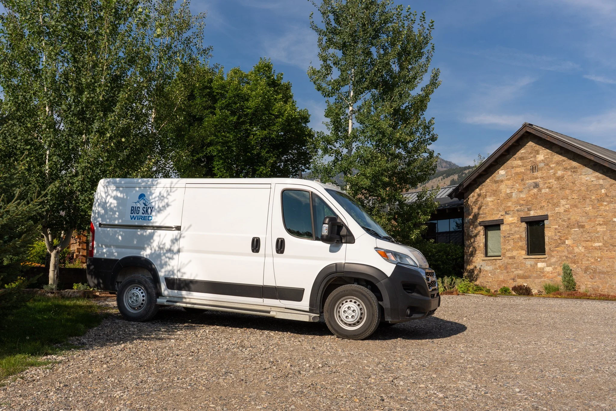 Big Sky Wired van parked in the driveway of a stone Montana home