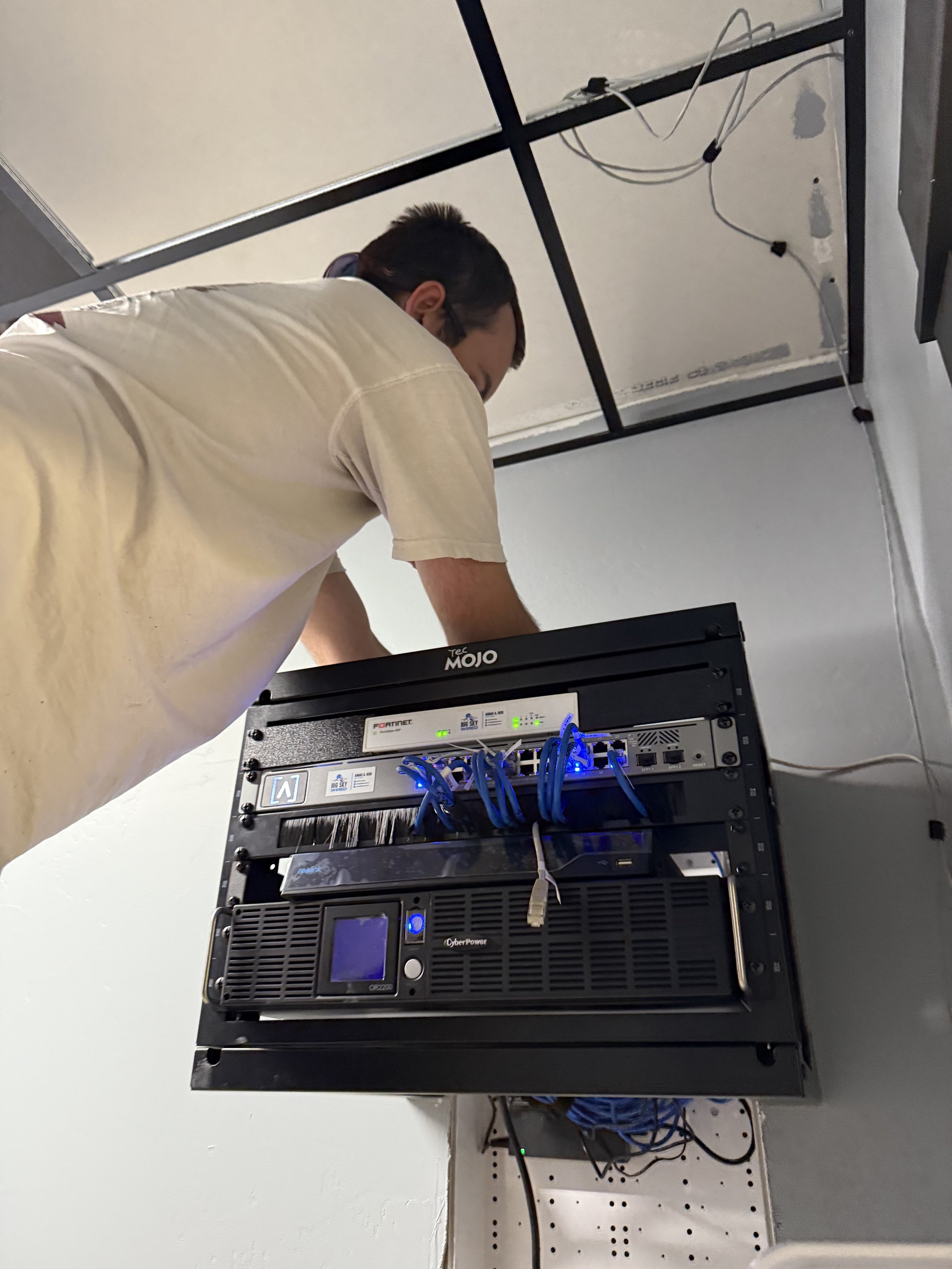 Big Sky Wired technician mounting a finished network rack in a commercial space