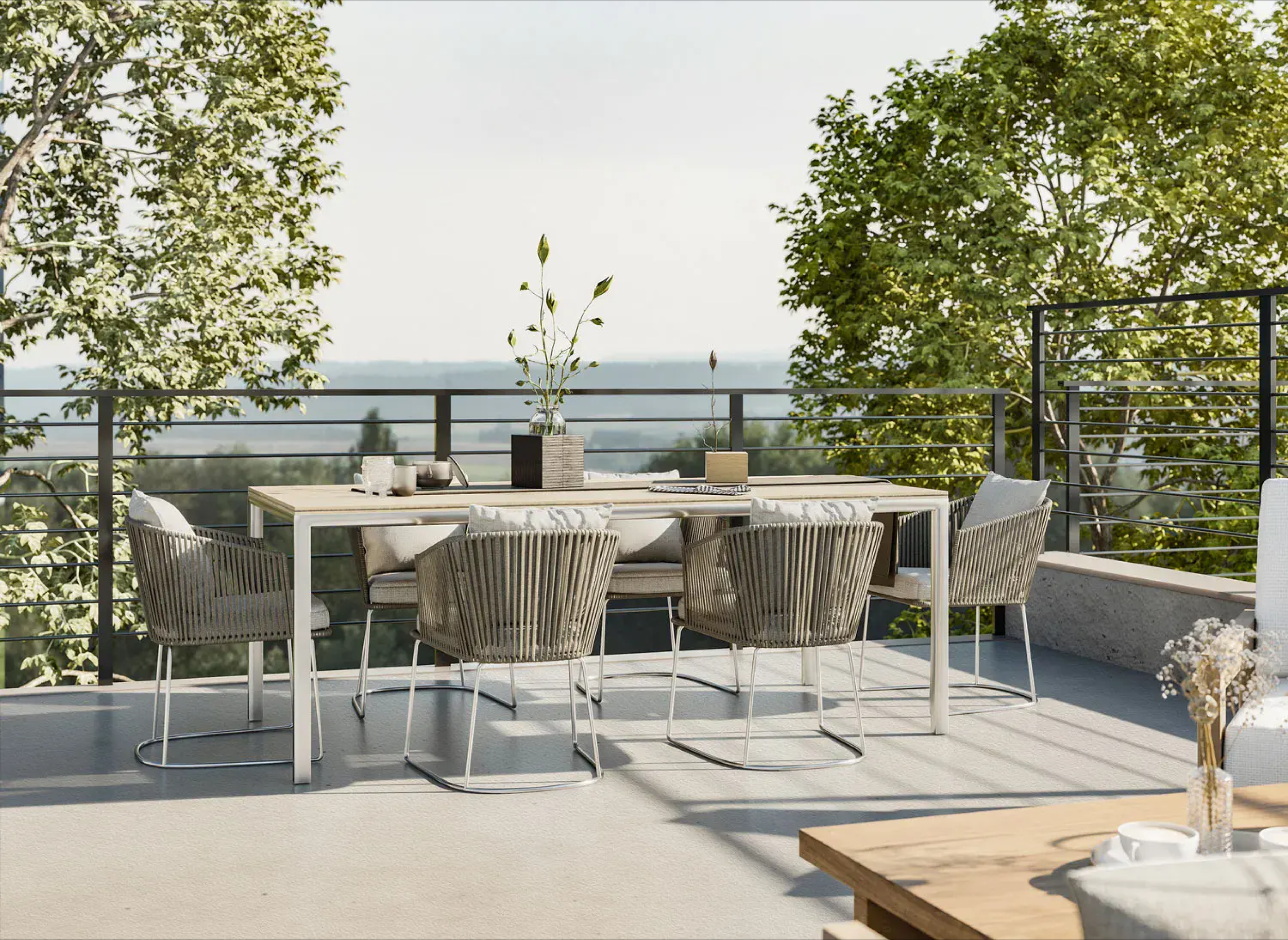 Rooftop patio with woven outdoor seating, neutral cushions, and patterned pillows, offering panoramic views of natural landscape; modern metal railing enhances open, serene atmosphere.