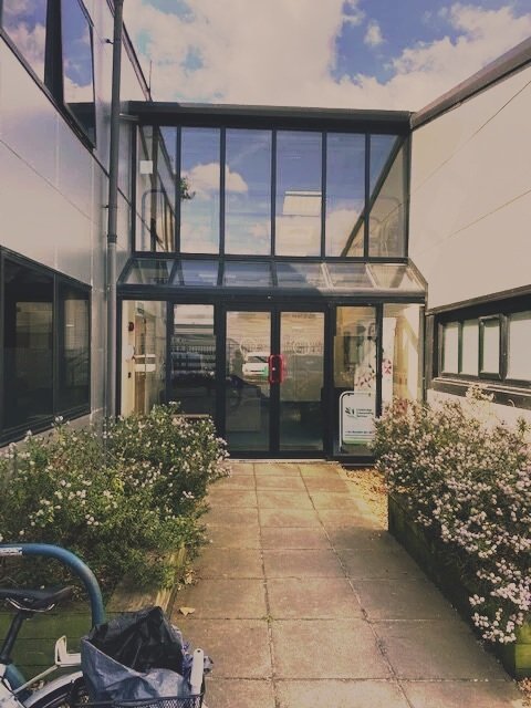 The front entrance to CCS, bushes and bike racks hold the edges of the pathway to the front door.