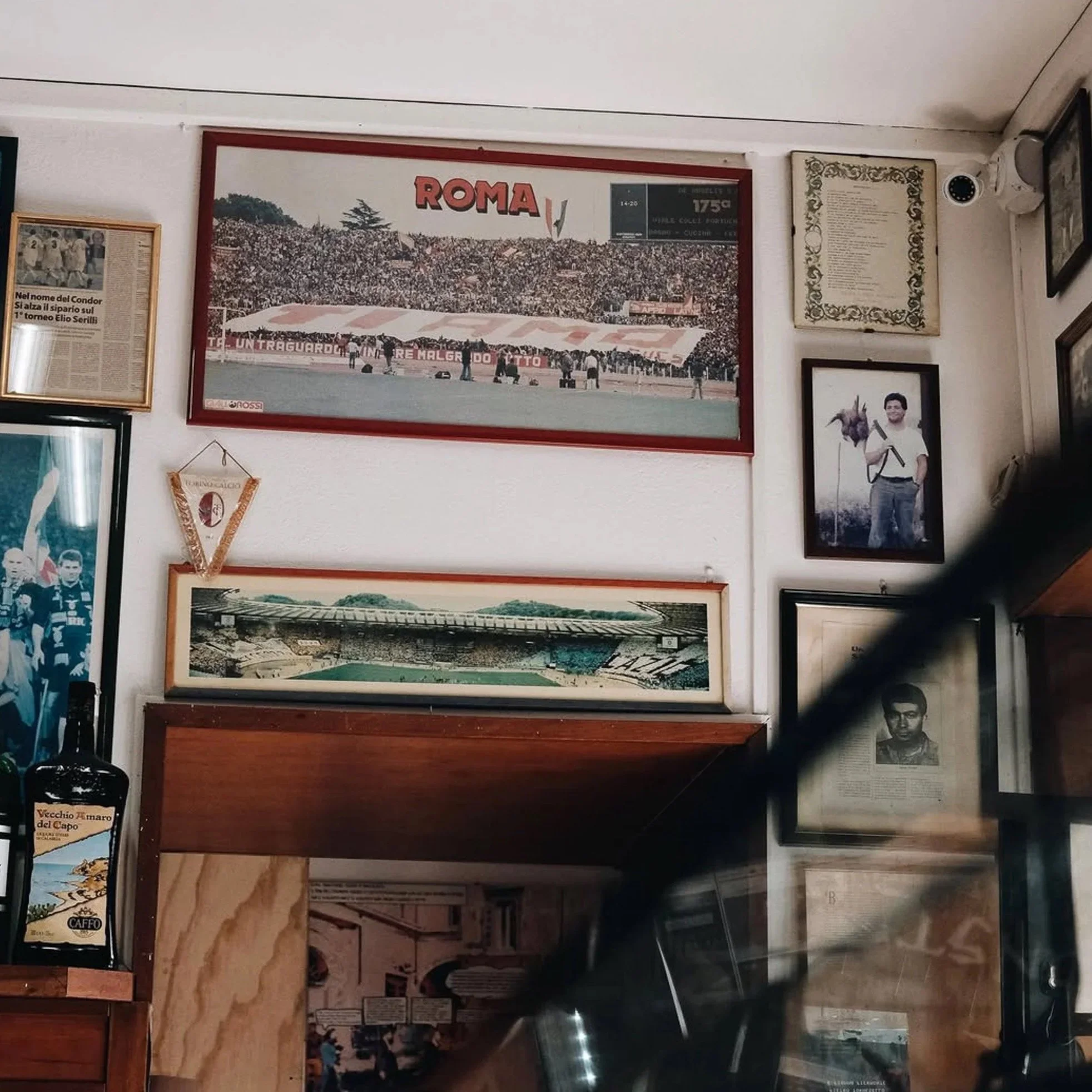 Atmospheric interior used for an analog photography workshop in Rome featuring vintage Roma stadium posters and framed photographs