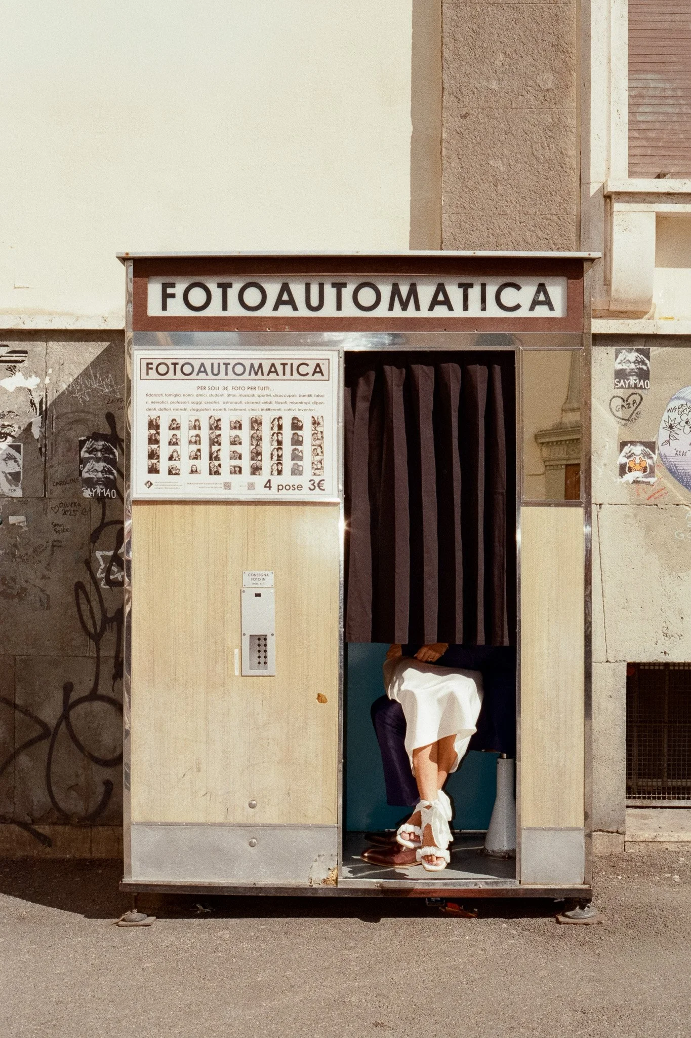 Film photograph of Gina and Kyle, a couple from South Africa, taken during their elopement wedding in Florence, Italy. Shot with a Contax G2, the image captures the couple inside a vintage Fotoautomatica booth, combining the intimacy of the wedding d