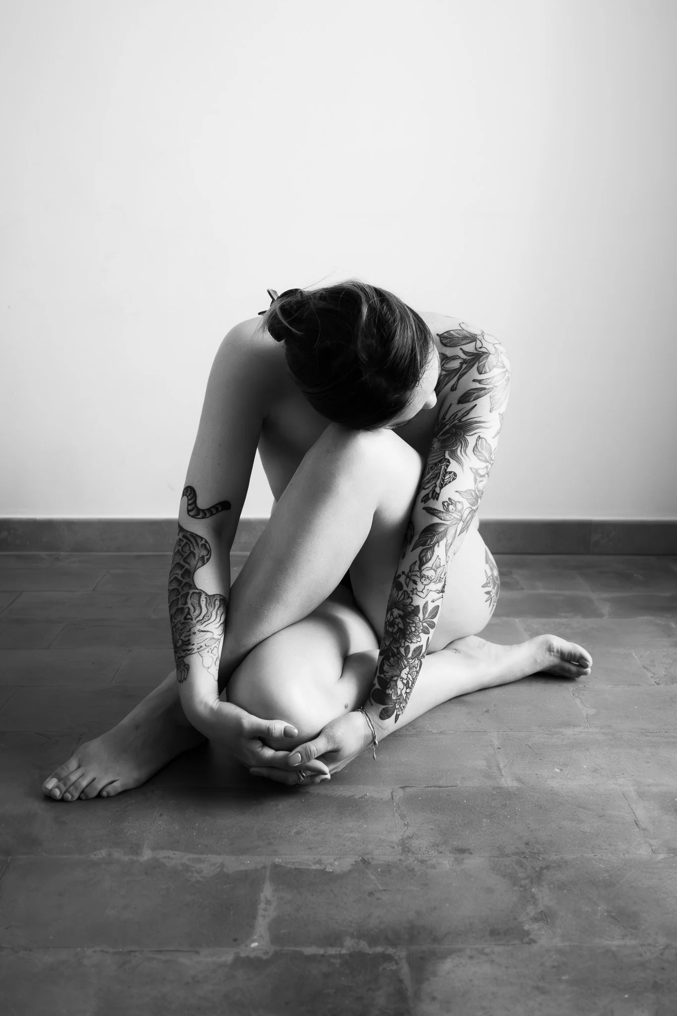A black and white fine art portrait photographed in Rome, focusing on the relationship between the human body, tattoos, form and natural light. Photography by Gökhan Kutluer.