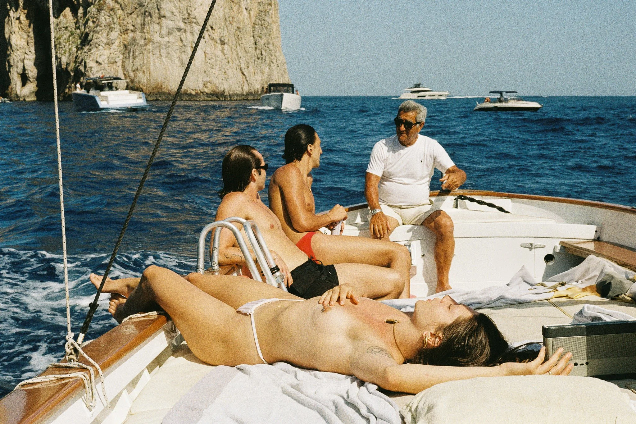 35mm film photograph taken in Capri with a Leica M6, capturing a relaxed summer moment aboard a boat off the island’s rocky coastline. The image reflects the warmth, color and effortless Mediterranean atmosphere of a day at sea.