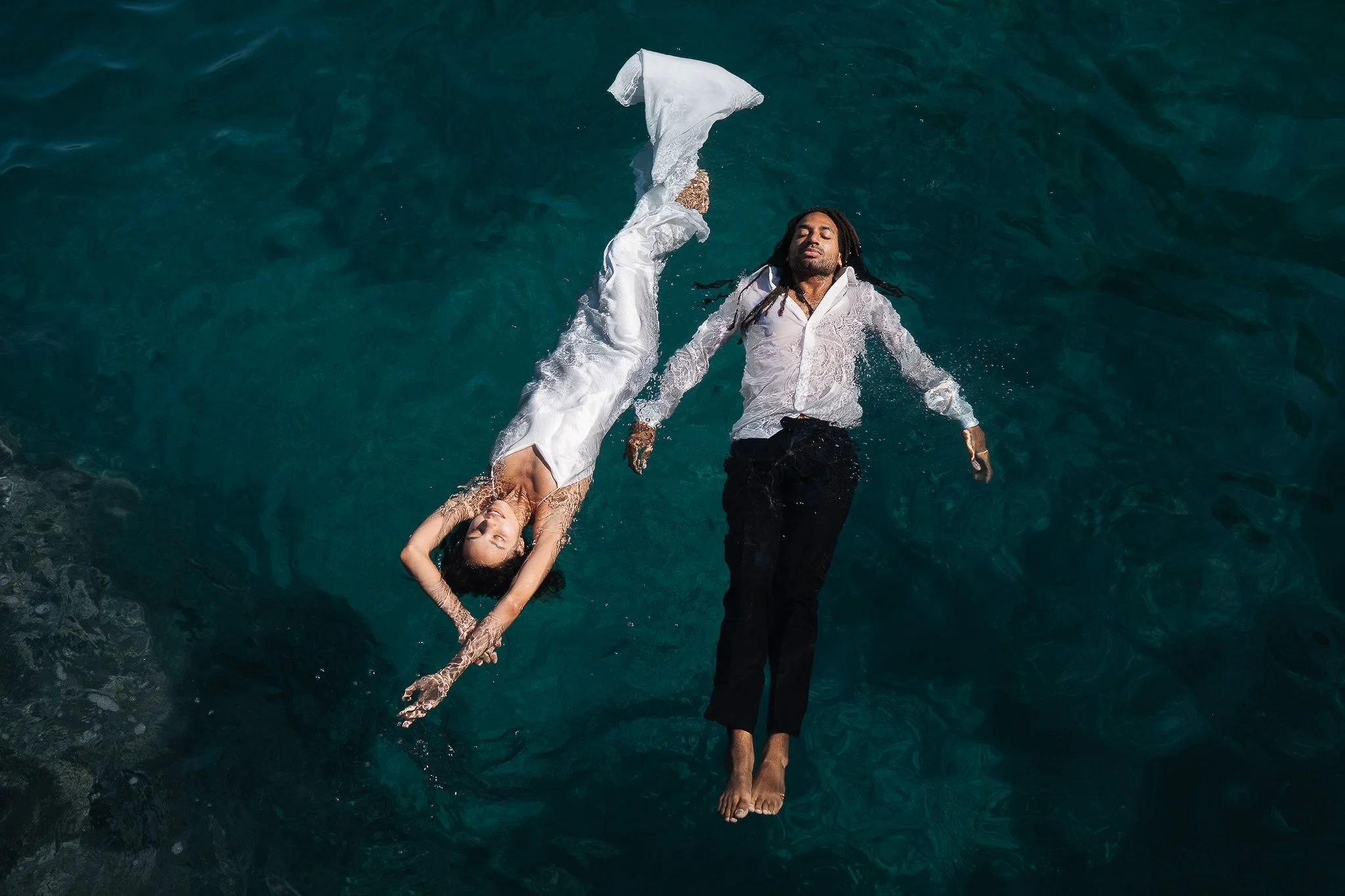 Wedding photograph taken in Sicily, capturing a couple floating together in the Mediterranean Sea in their wedding clothes. The image reflects freedom, intimacy and spontaneity, turning the wedding day into a quiet and unconventional moment in the wa