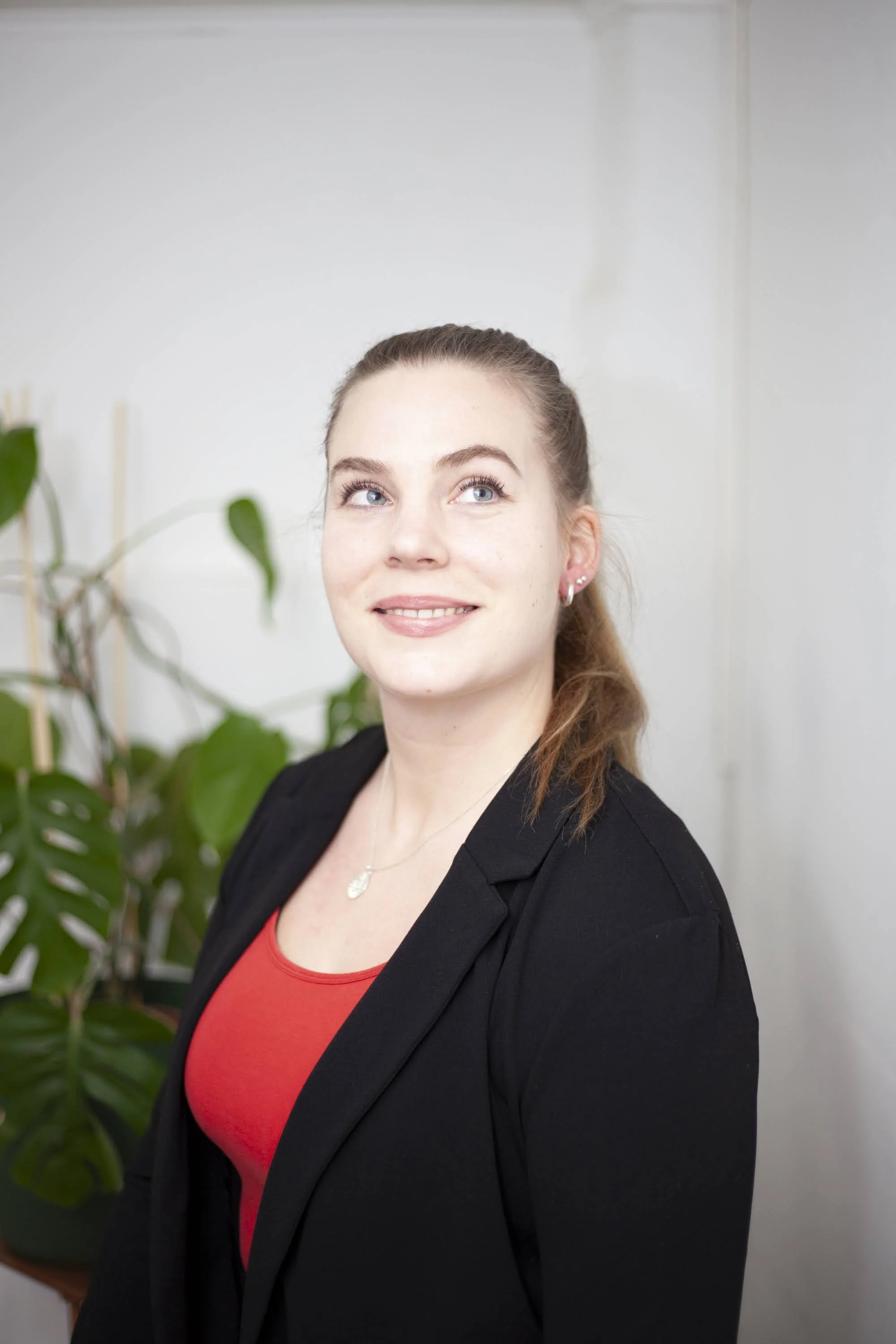 Kirjanpitäjä, joka hymyilee Lotteri Oy:n brändikuvauksissa. Hänellä on siniset silmät ja hän on pukeutunut punaisiin ja mustiin vaatteisiin.