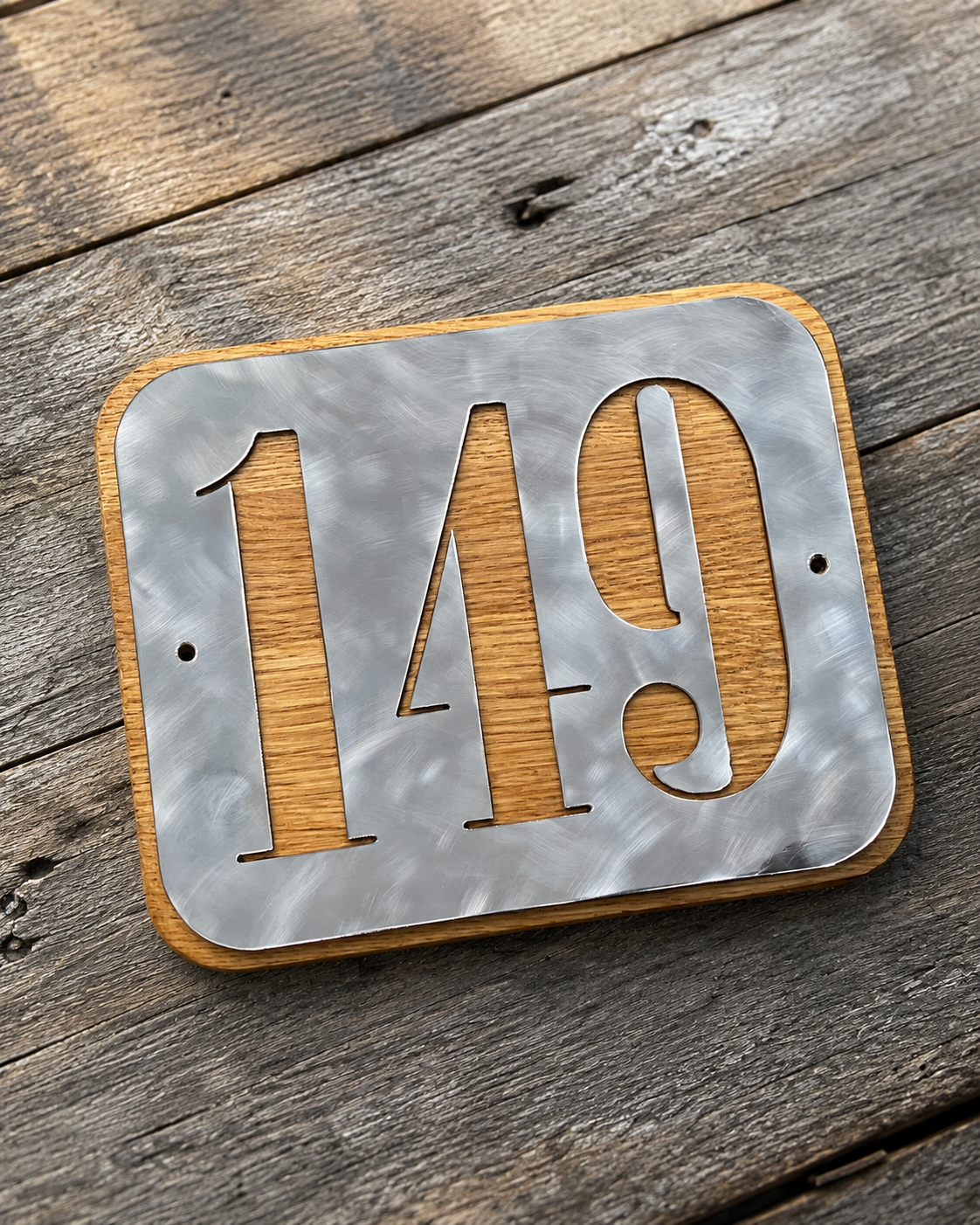 A decorative house number sign displaying '149' with metal numbers and a wood background on a wooden surface.