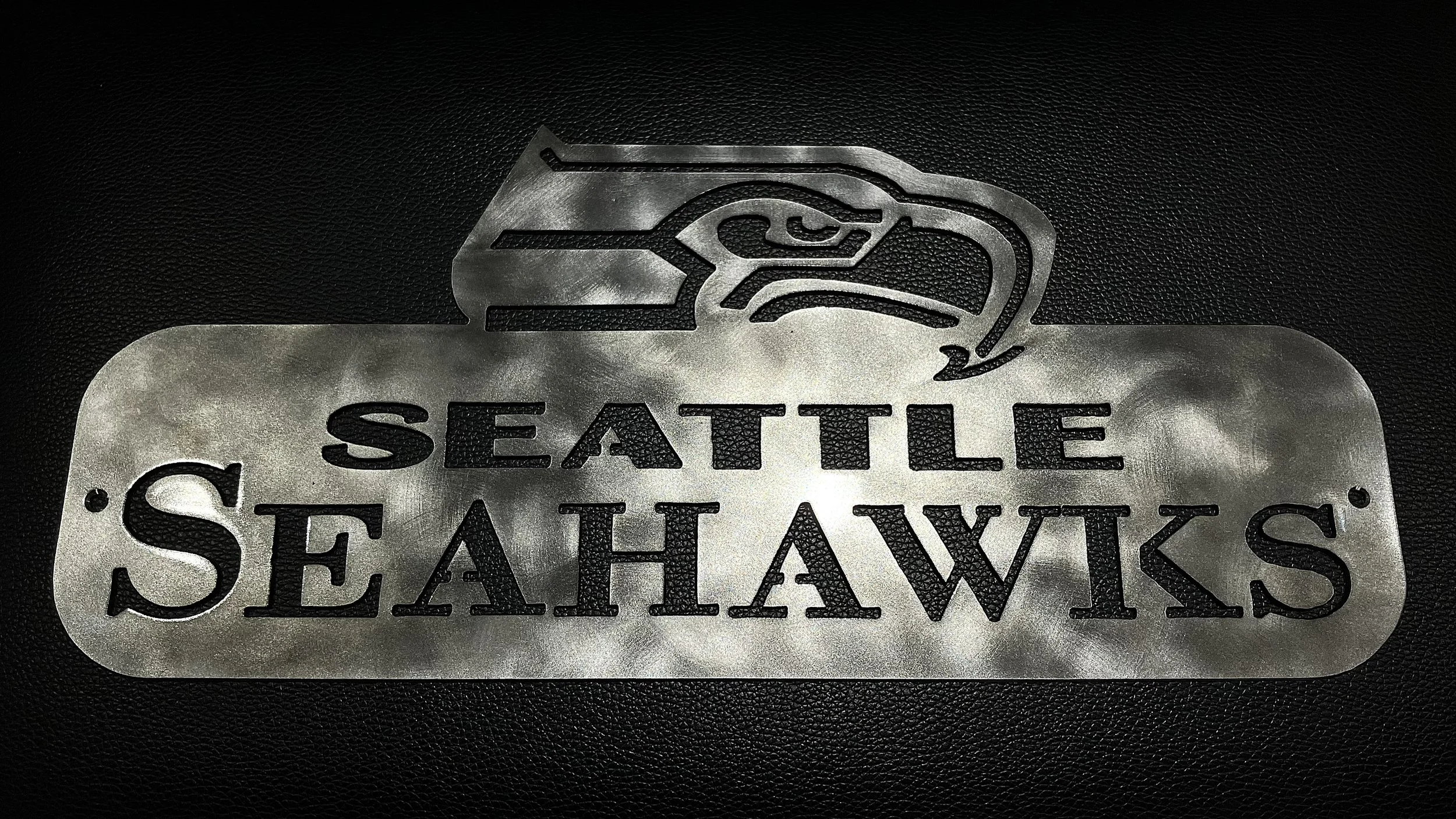 Metal sign with the Seattle Seahawks logo and text.
