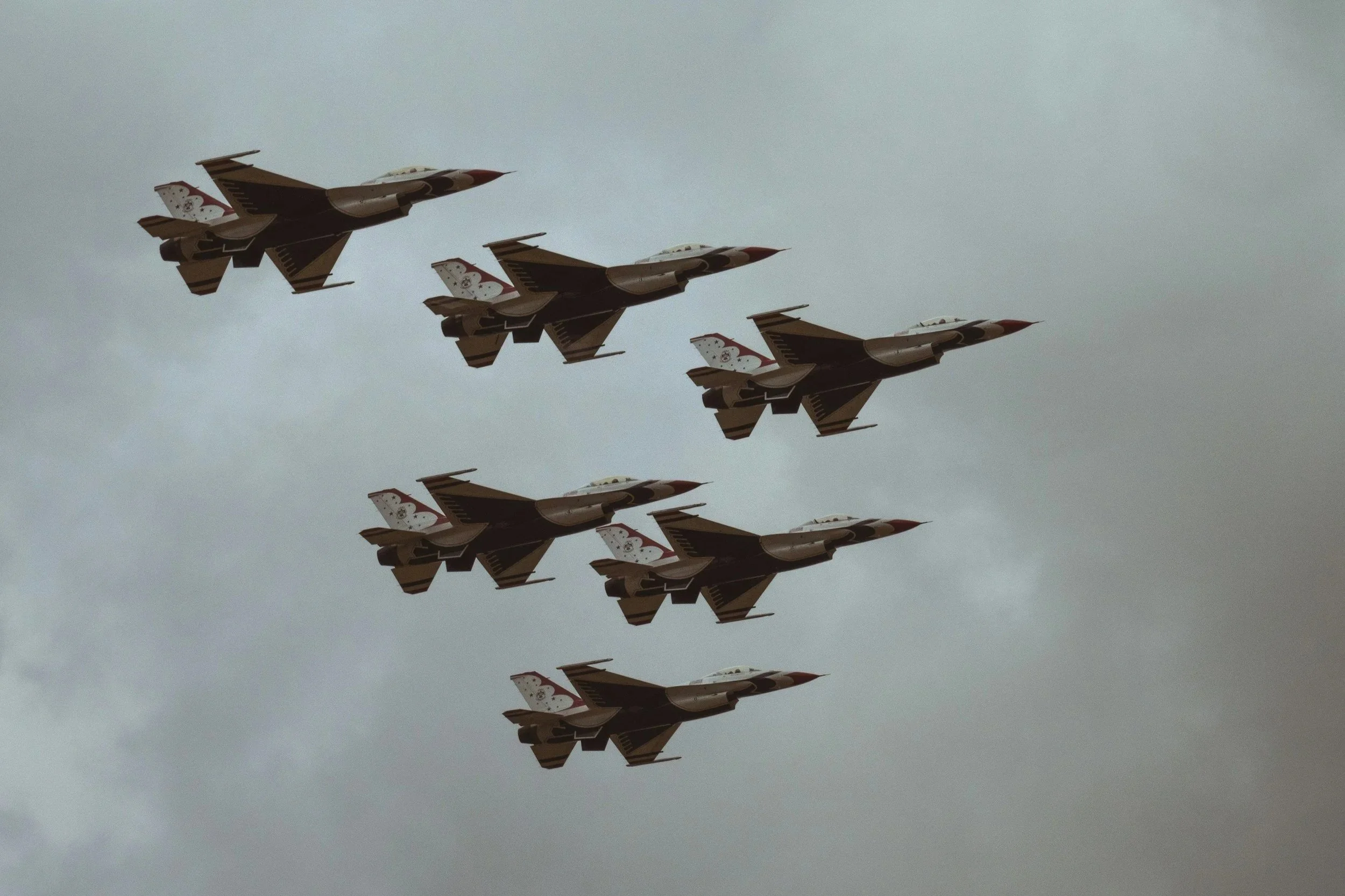 Six fighter jets flying in a formation against a cloudy sky.